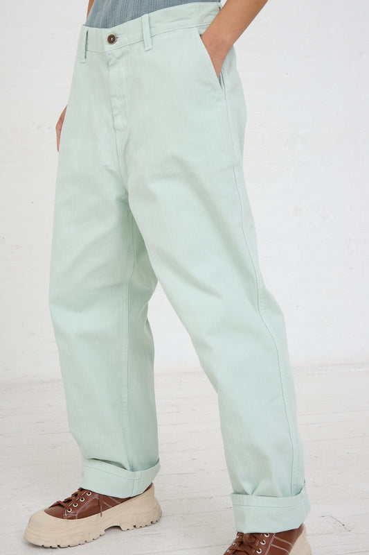 A person standing sideways showcasing the Herringbone Garment Dye Pant in Ice Green by Ichi Antiquités and brown shoes.