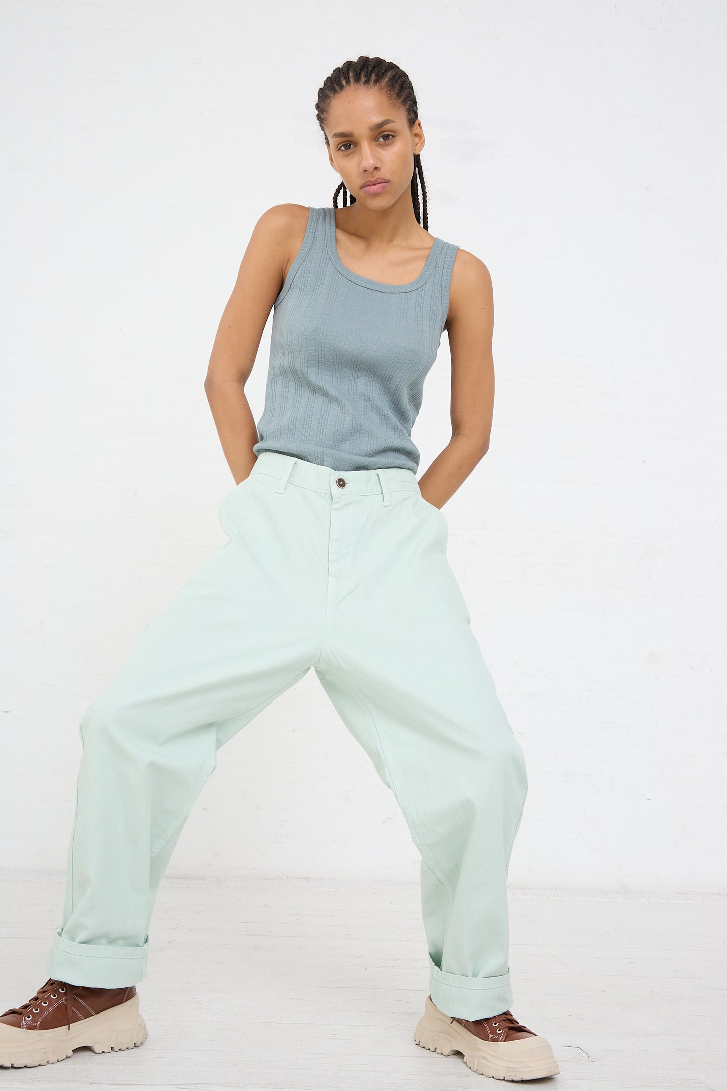 Woman posing in the Ichi Antiquités Herringbone Garment Dye Pant in Ice Green and a gray tank top against a white background.