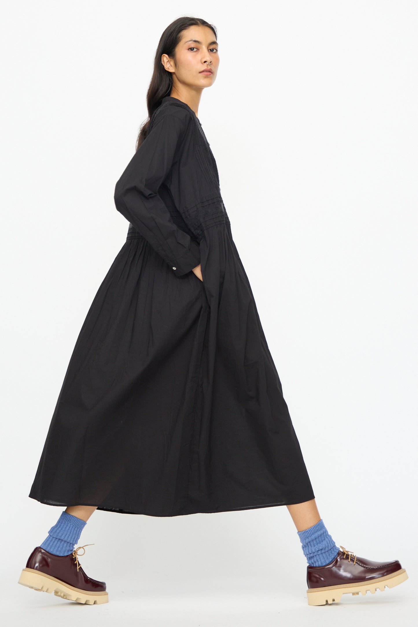 A person wears the Ichi Antiquités India Cotton Dress in Black with blue socks and brown platform shoes, walking against a white background.
