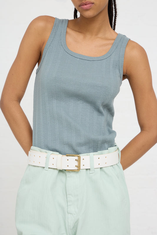 Woman wearing a sleeveless ribbed top and light-colored Ichi Antiquités belted trousers with a White Leather Belt from Ichi Antiquités with a brass buckle.