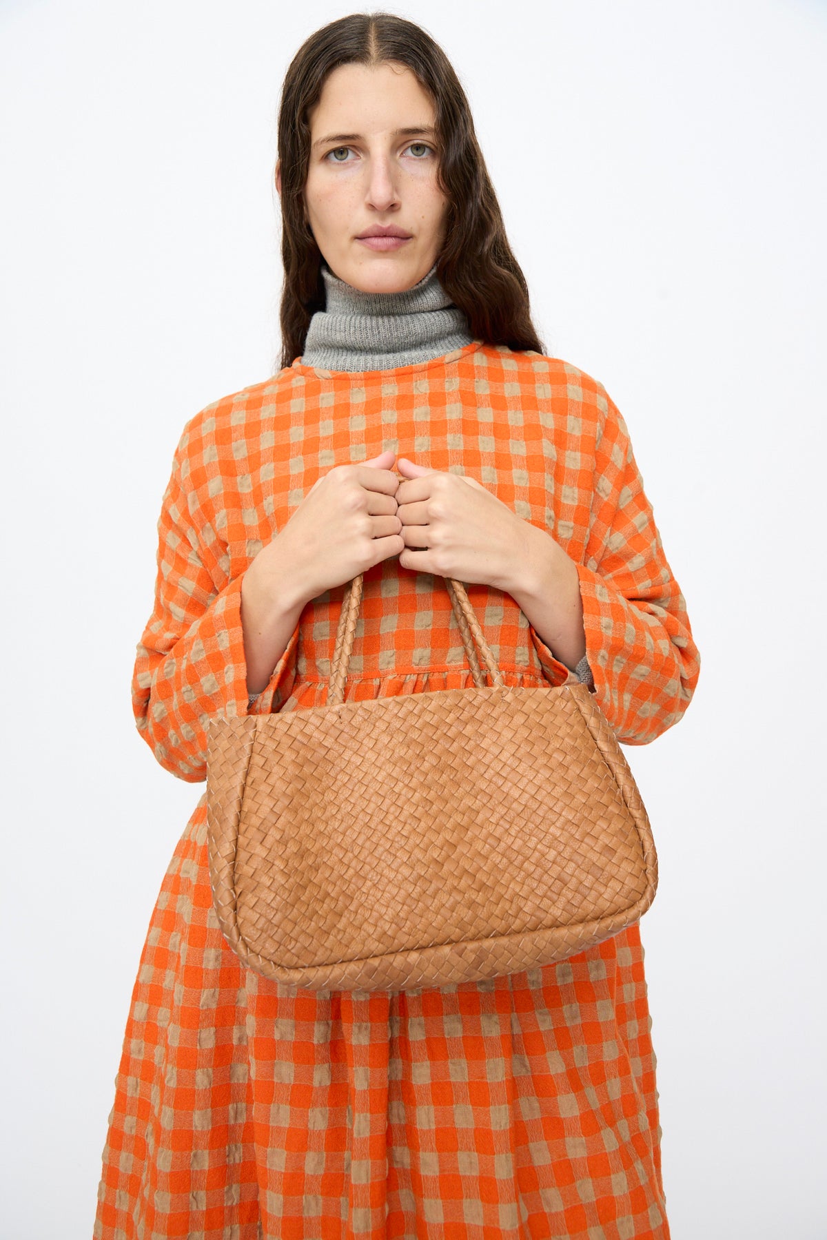 A person holds a small, woven Ichi Antiquités Leather Tote Bag in Brown.