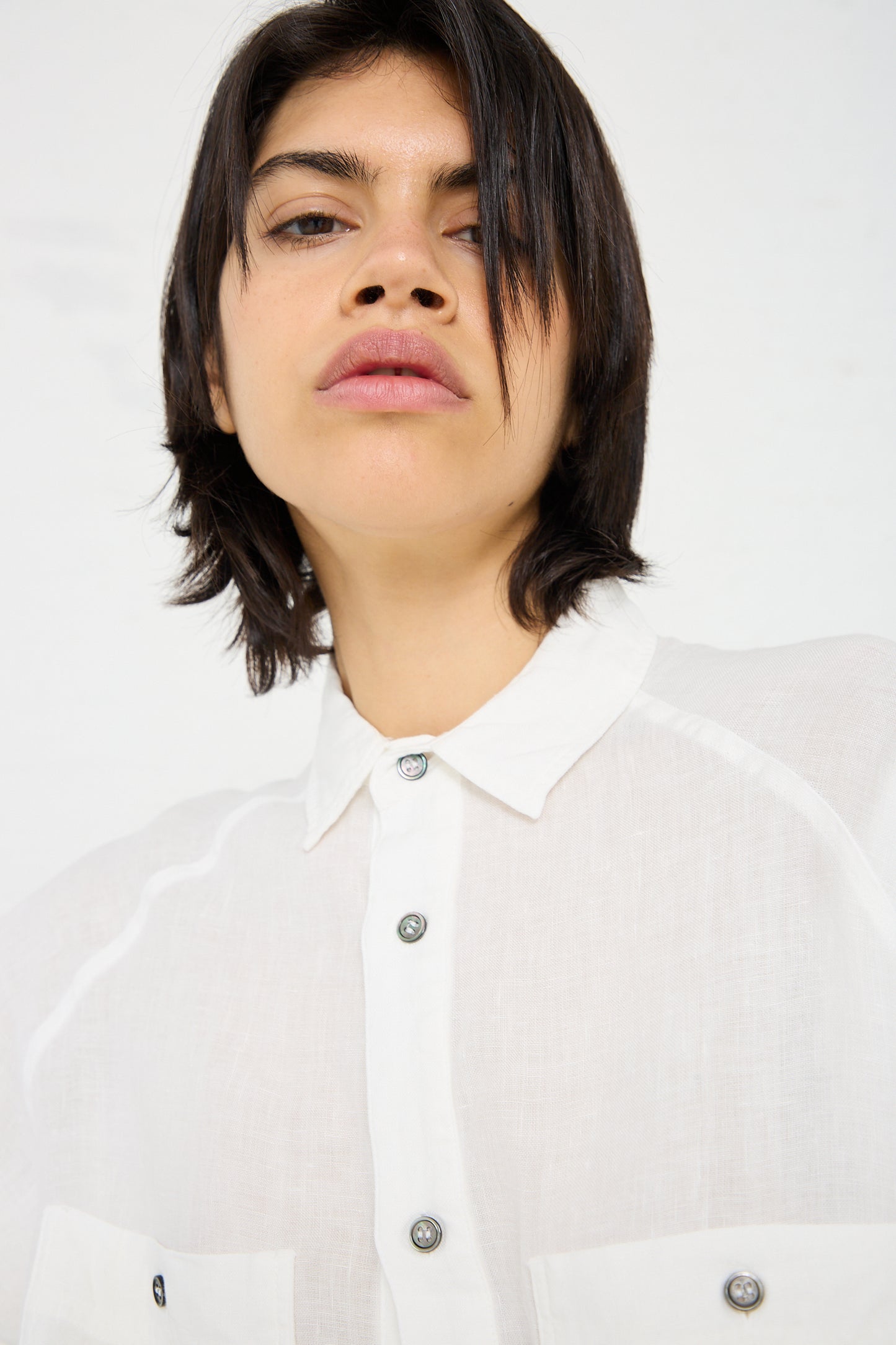 Person with short dark hair wearing a white, Linen Canvas Overdye Shirt in White by Ichi Antiquités, looking directly at the camera against a plain white background.