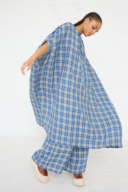 Woman in an oversized Ichi Antiquités Linen Check Dress in Dark Indigo and Natural Linen twirling while standing against a white background.