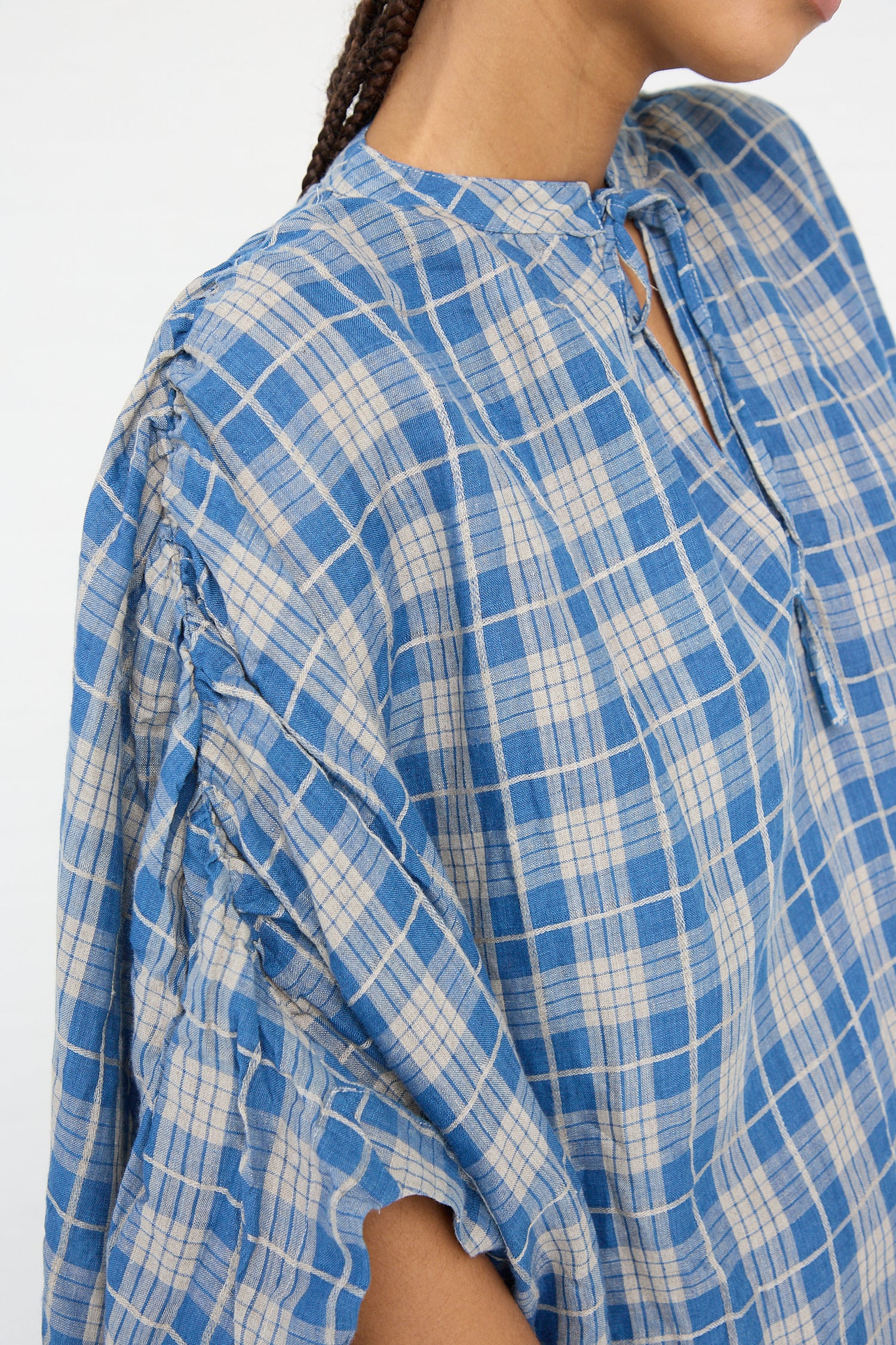 Close-up of a person wearing a Linen Check Dress in Dark Indigo and Natural Linen by Ichi Antiquités with stitched details on the shoulder.