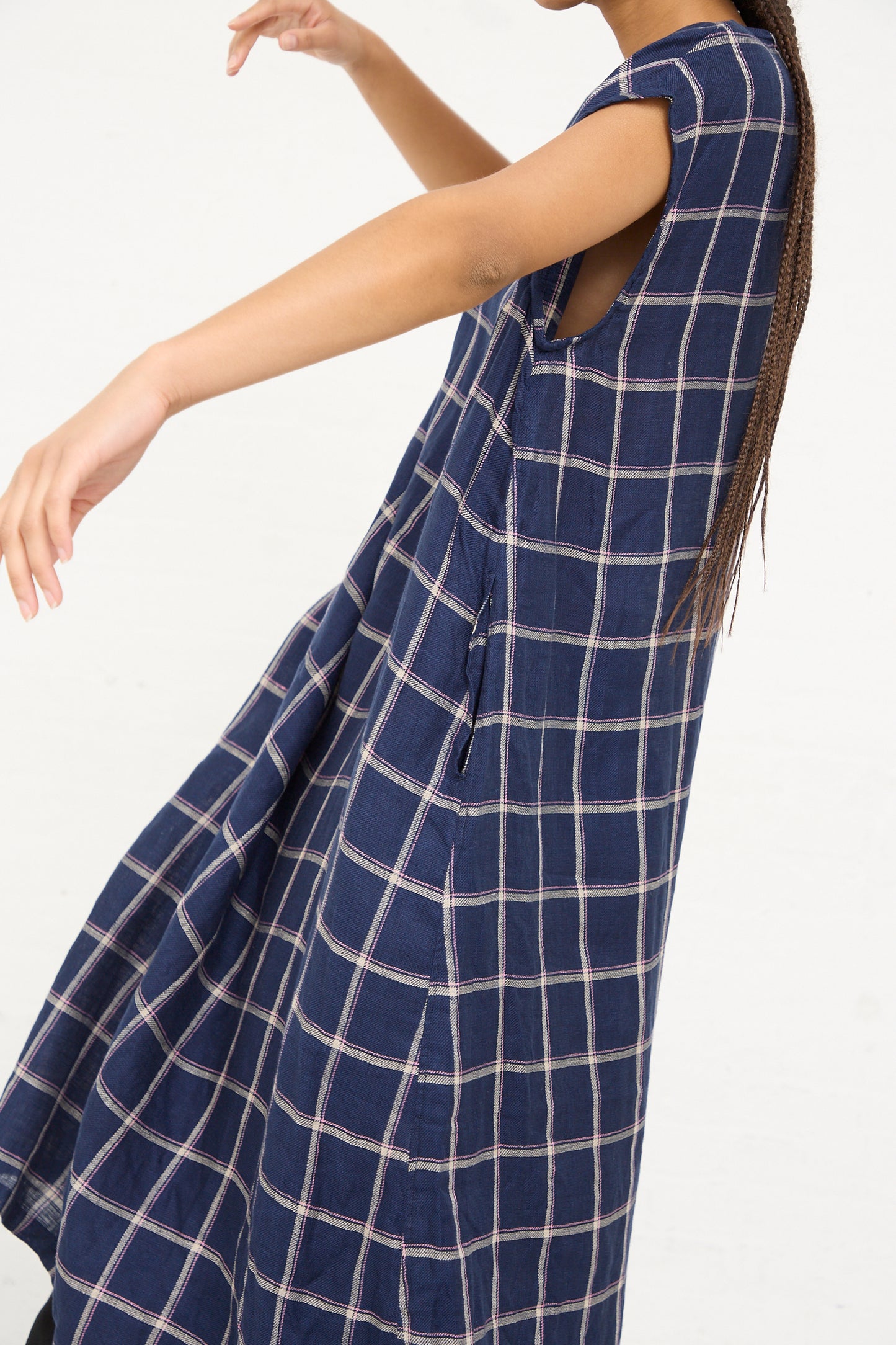 Woman modeling an Ichi Antiquités navy check linen dress with one arm extended.