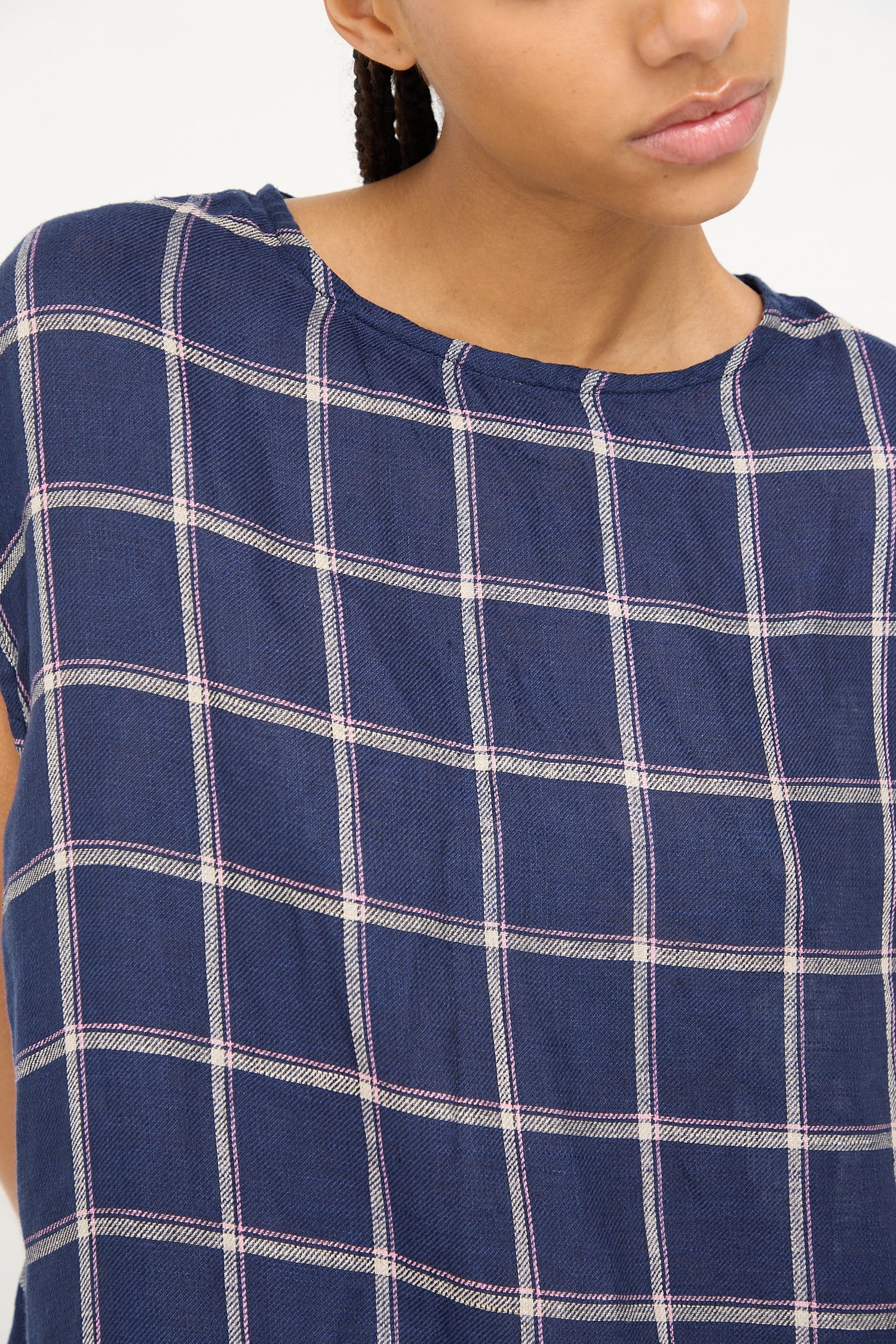 Close-up of a woman wearing a navy linen check dress from Ichi Antiquités with a focus on the fabric and pattern.