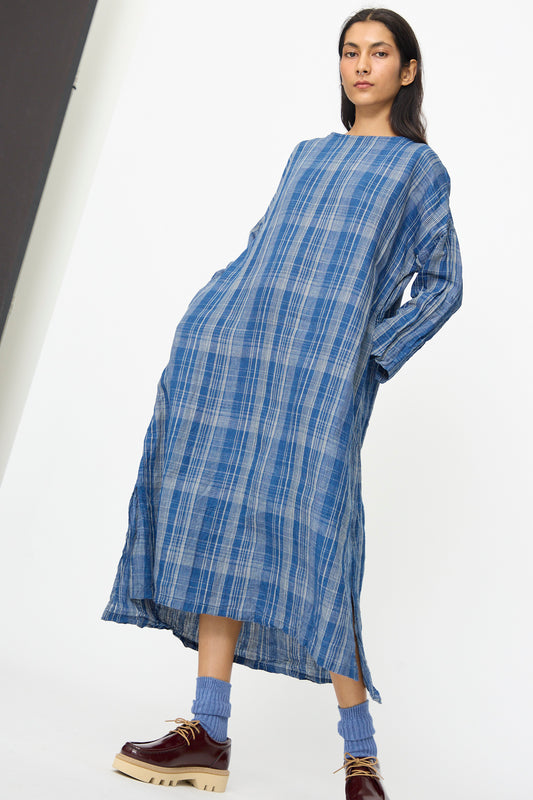 A person wears the Linen Check Dress in Navy Indigo by Ichi Antiquités—relaxed fit with side slits—paired with blue socks and brown platform shoes, standing against a plain white background.