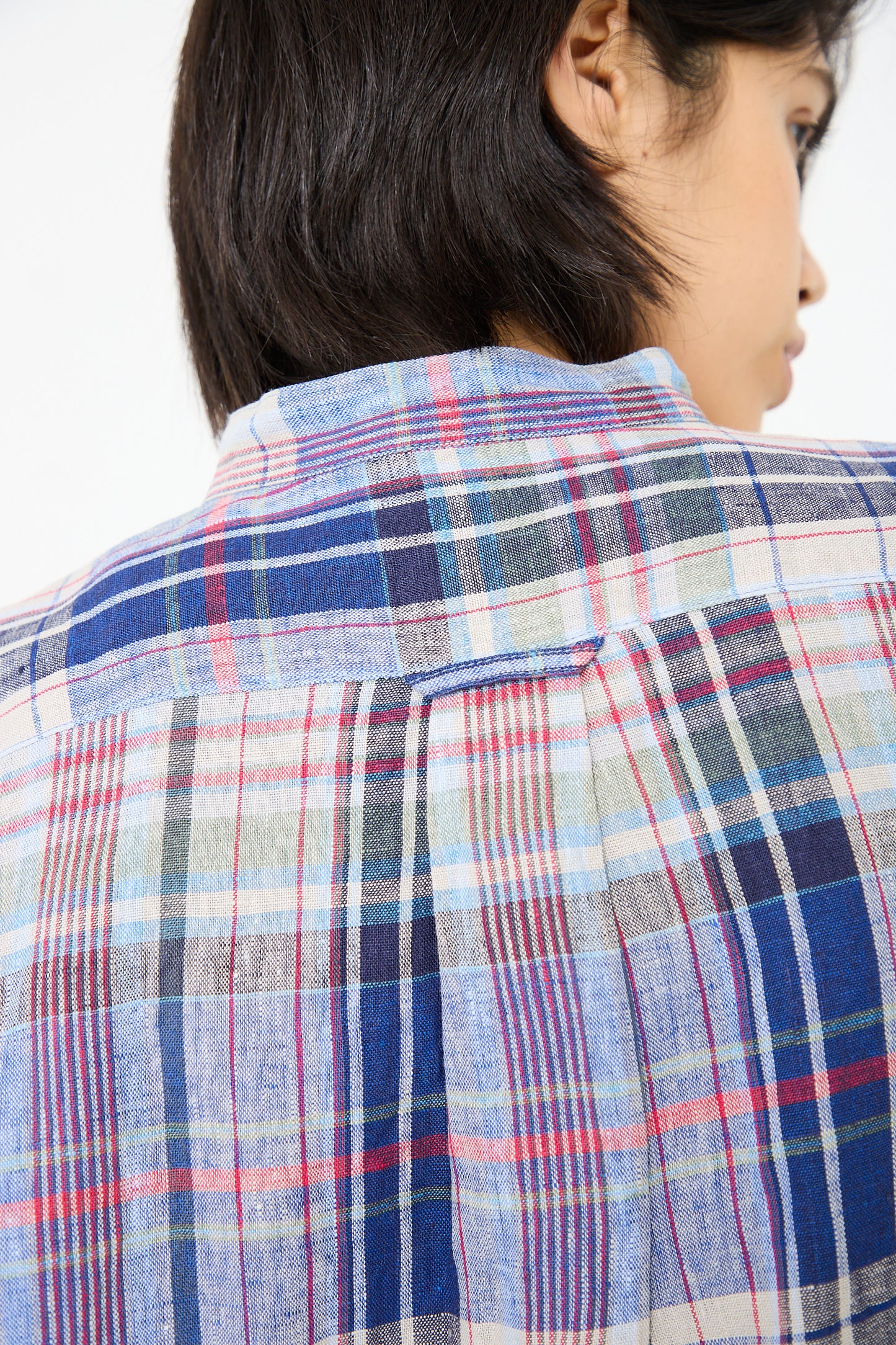 Close-up of a person wearing an Ichi Antiquités Linen Check Shirt in Navy, viewed from the back. The shirt's band collar adds a touch of style. The person has short black hair, and a portion of their face is partially visible.