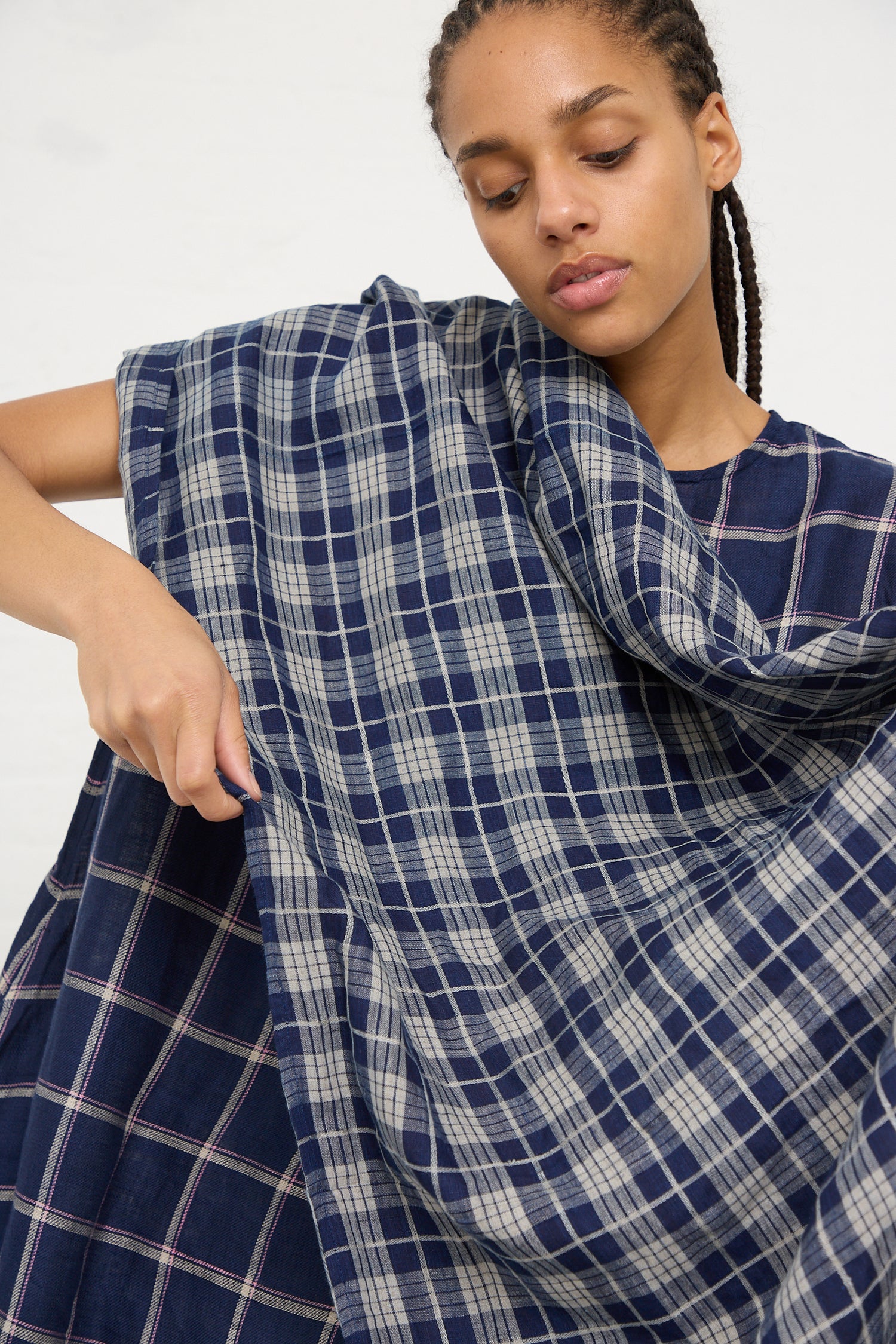 A woman examining the natural fibers of a blue plaid Ichi Antiquités Linen Check Stole in Dark Indigo and Natural.