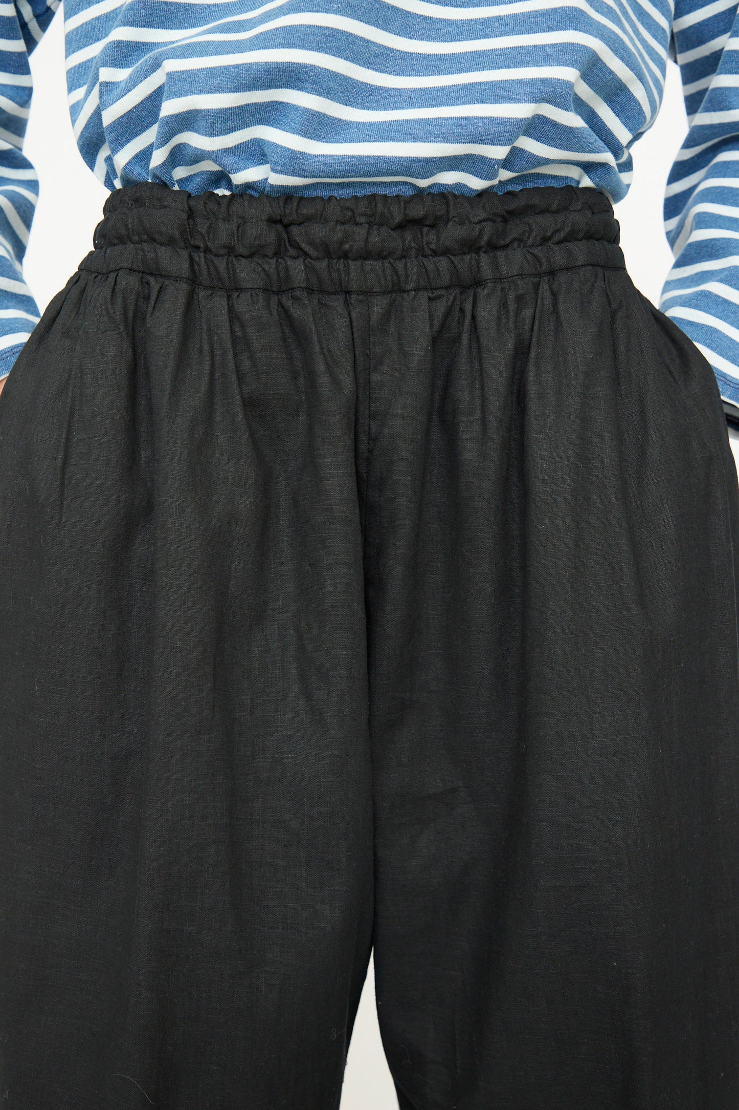 Person wearing a blue and white striped shirt tucked into high-waisted Ichi Antiquités Linen Cotton Canvas Pant in Black with an elastic waistband.