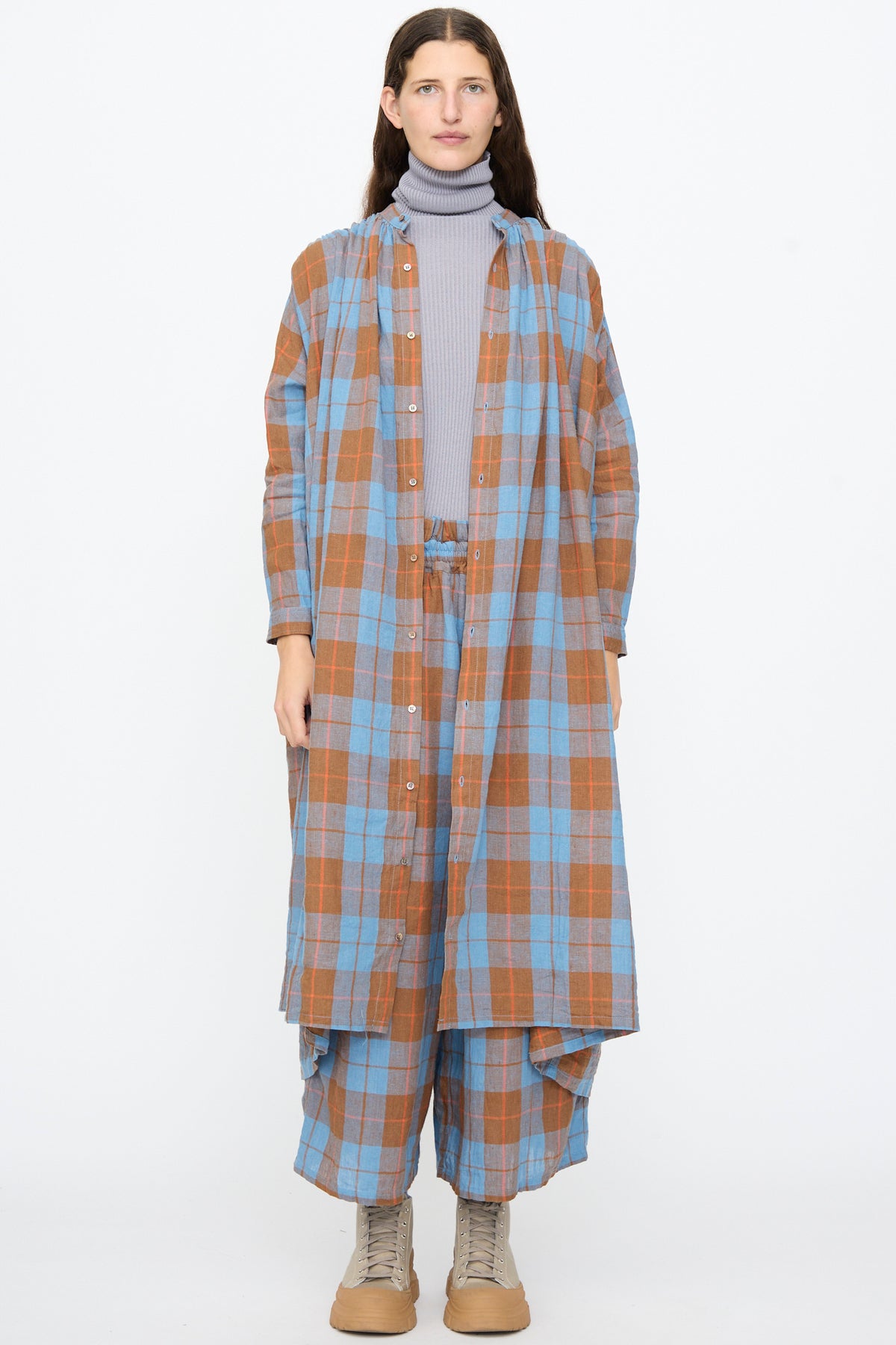 A person wearing an Ichi Antiquités Linen Cotton Check Dress in Blue over a grey turtleneck with matching plaid wide-leg trousers.