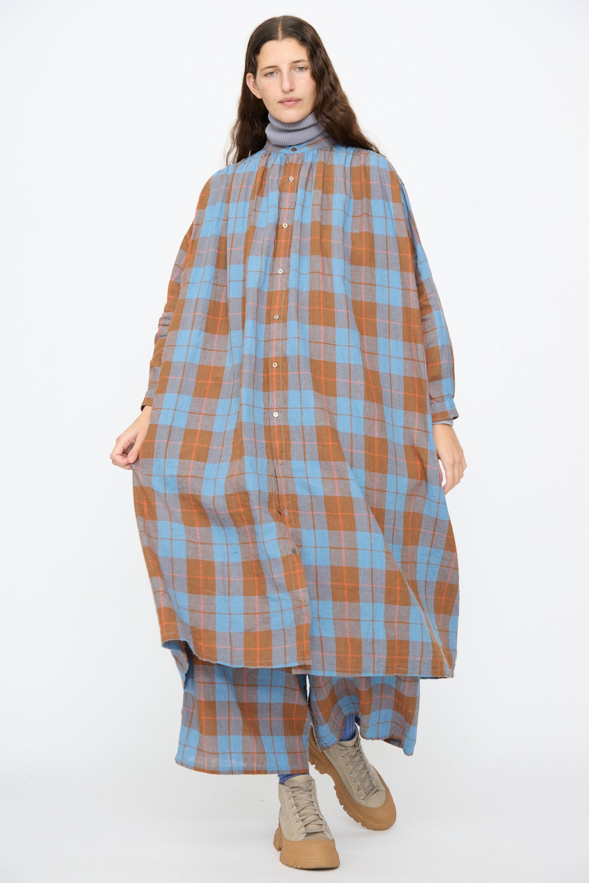 A person wears an Ichi Antiquités Linen Cotton Check Dress in Blue over matching plaid wide-leg trousers and tan lace-up boots.
