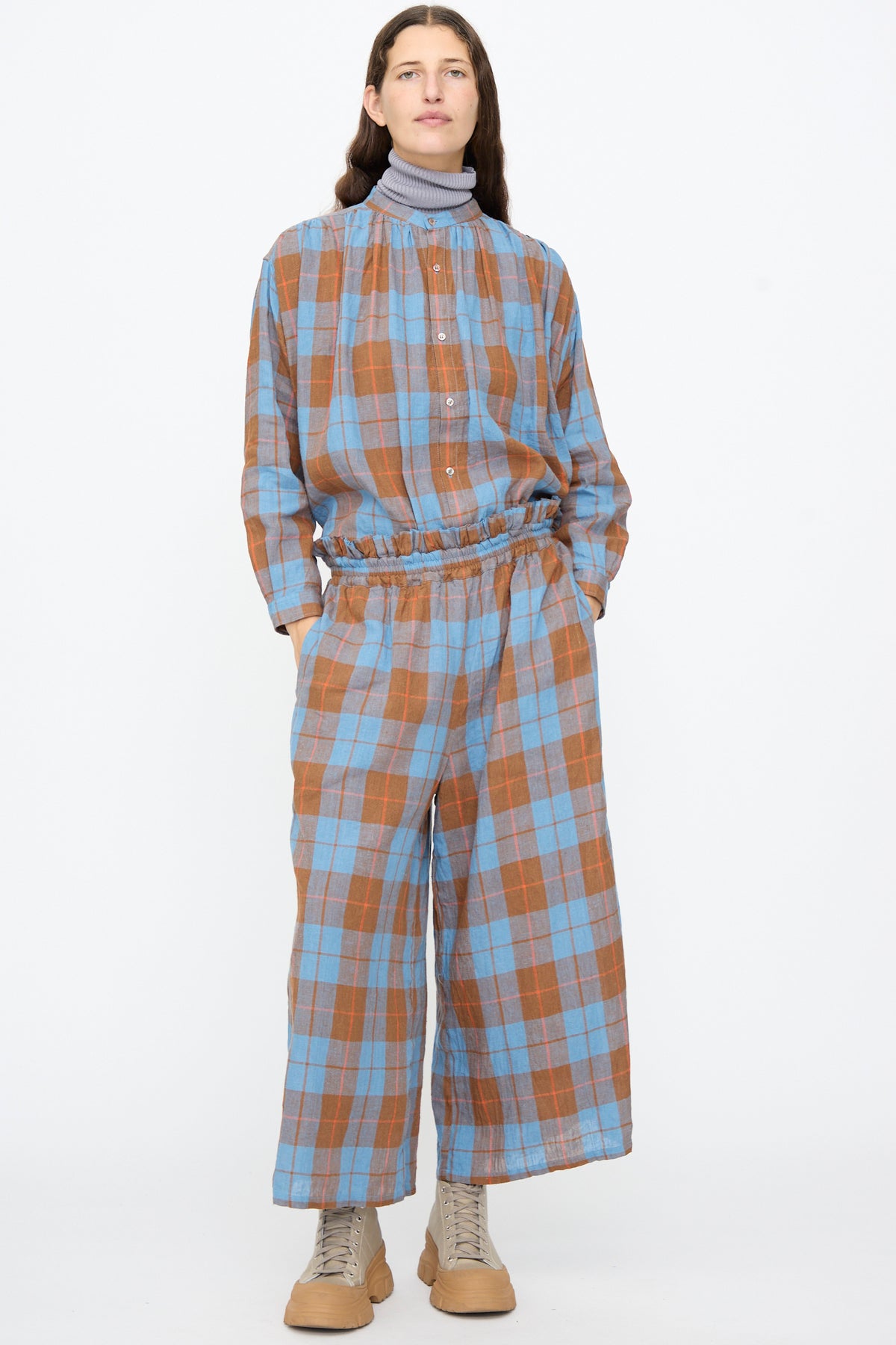 A model wearing a blue and brown plaid button-down shirt and matching Ichi Antiquités Linen Cotton Check Pants in Blue, featuring a cropped wide-leg cut and an elastic waistband.