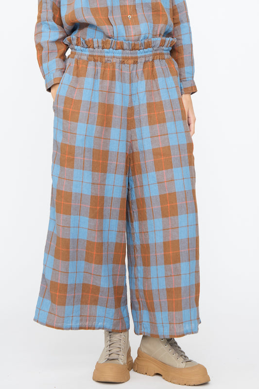Person wearing Ichi Antiquités Linen Cotton Check Pants in Blue, featuring a cropped wide-leg fit and elastic waistband, paired with beige sneakers.