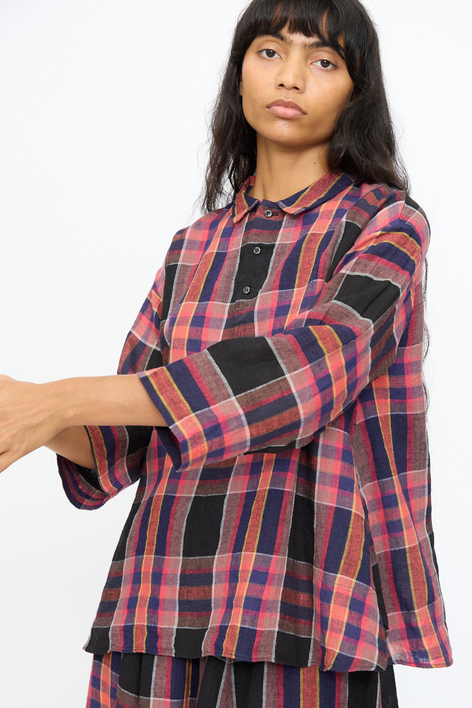 A person wears the Ichi Antiquités Linen Cotton Check Shirt in Black, a loose-fitting, long sleeve made-in-Japan top with red, black, and yellow plaid stripes, standing against a plain white background.