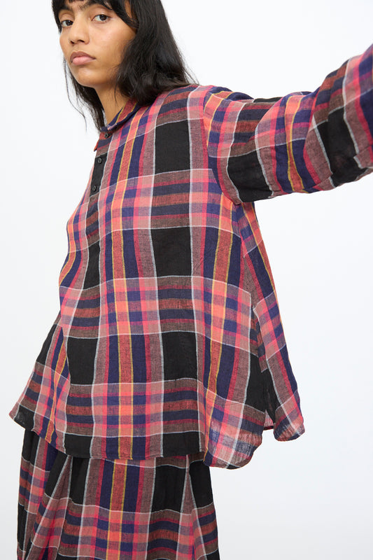 A person wears the Ichi Antiquités Linen Cotton Check Shirt in Black, featuring a loose fit and long sleeves, styled with a matching skirt in red, black, and yellow plaid against a plain white background.