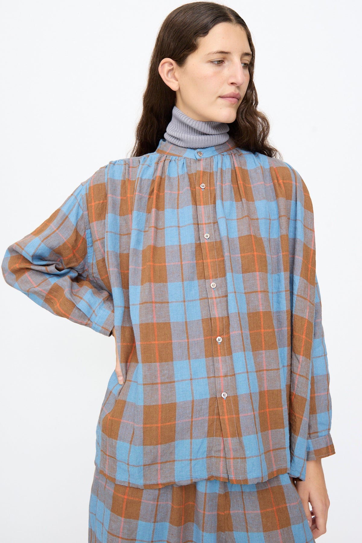 Ichi Antiquités Linen Cotton Check Shirt in Blue, featuring a long-sleeved blue and brown plaid gingham pattern worn over a gray turtleneck.