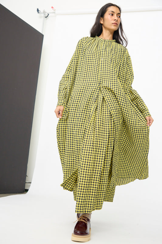 A person wears the Ichi Antiquités Linen Cotton Gingham Check Dress in Yellow, styled with maroon platform shoes, standing in a studio with a white backdrop.