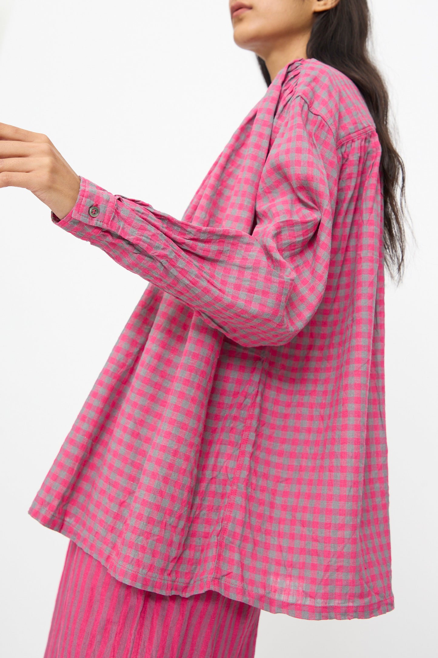 A person wears the Ichi Antiquités Linen Cotton Gingham Check Shirt in Pink, featuring a loose fit and band collar, paired with pink striped pants against a white background.