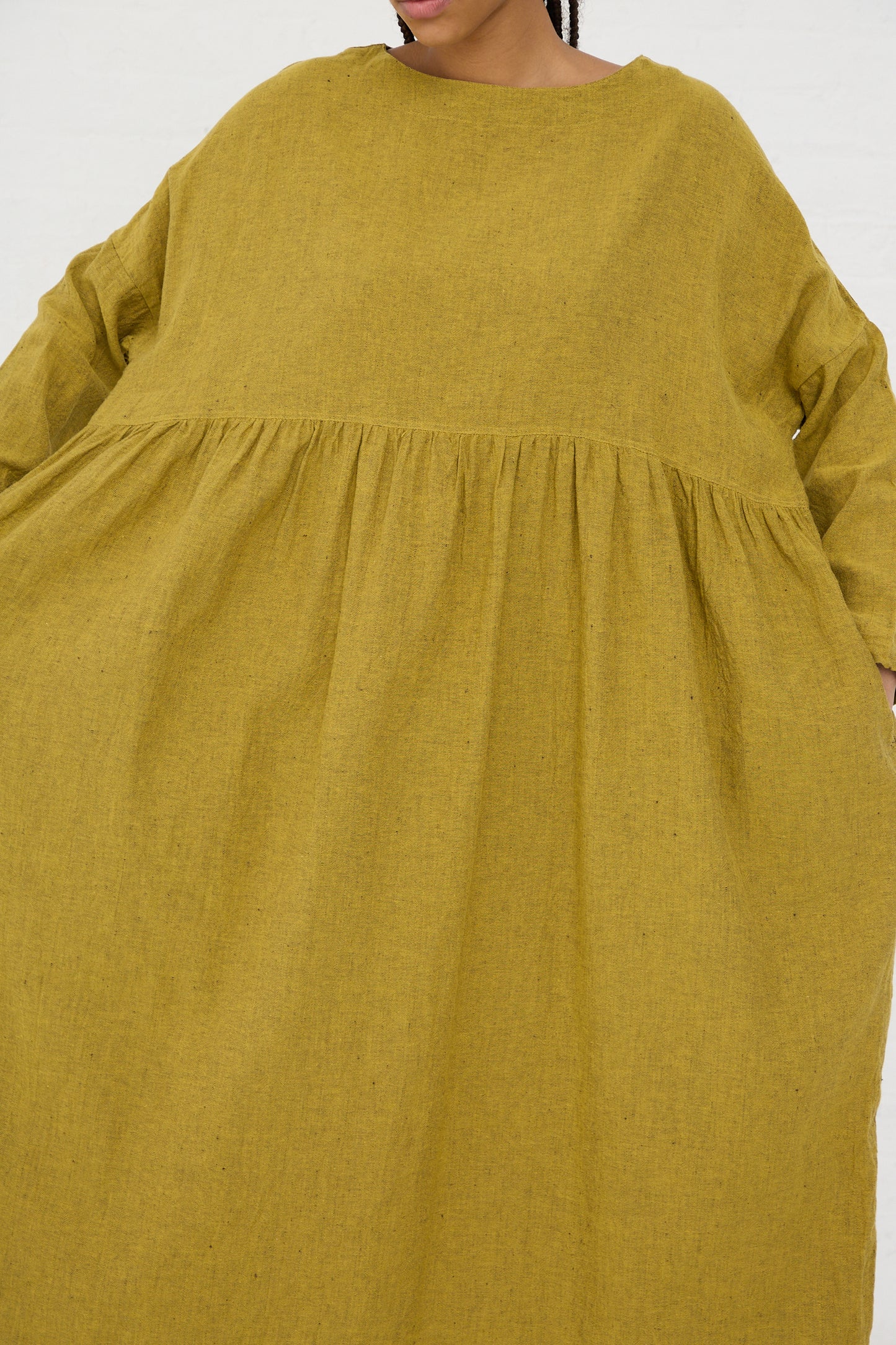 Woman wearing an oversized yellow linen cotton herringbone dress with gathered waist detail by Ichi Antiquités.