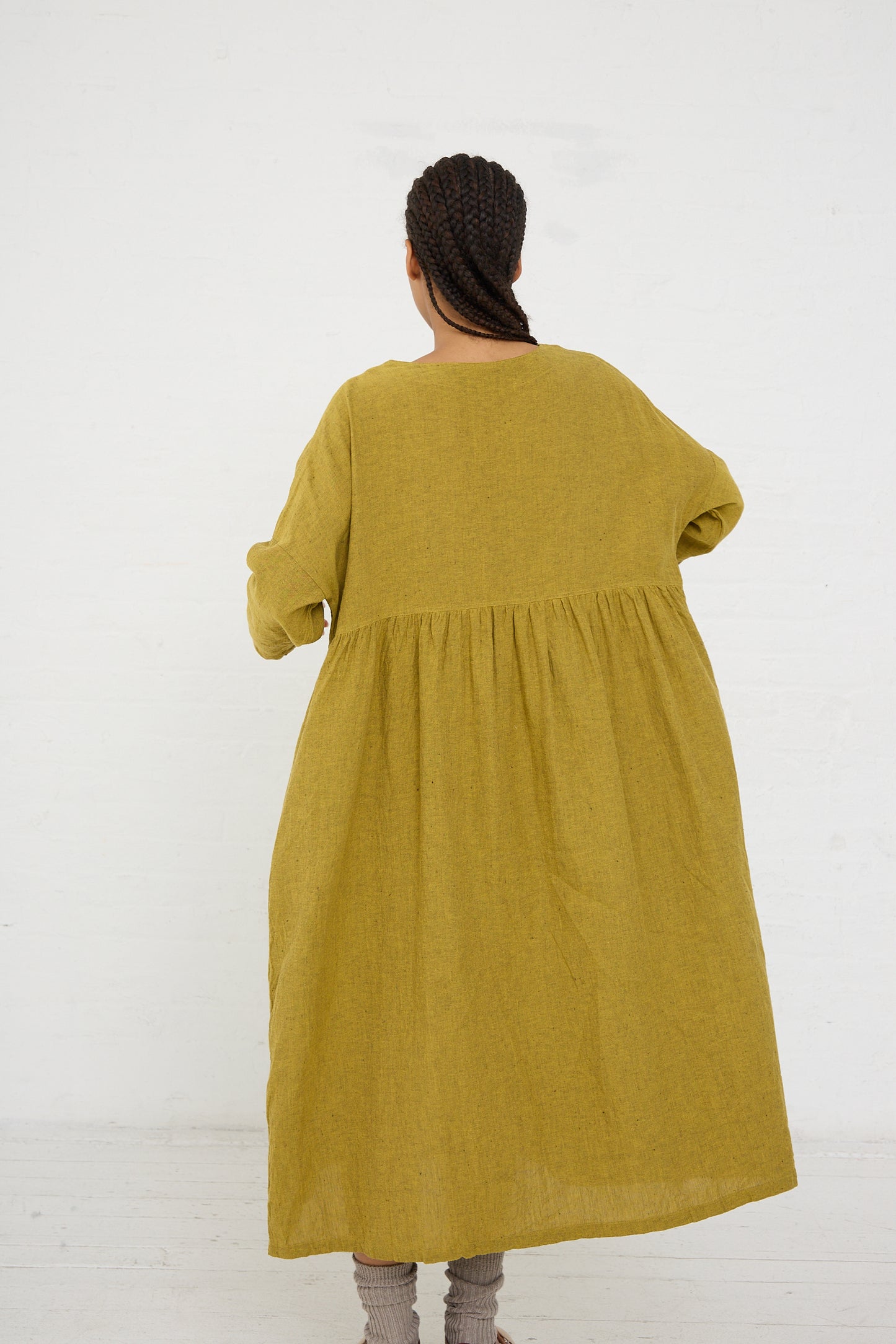 Woman standing with her back to the camera, wearing a Ichi Antiquités Linen Cotton Herringbone Dress in Yellow with gathered waist detail.