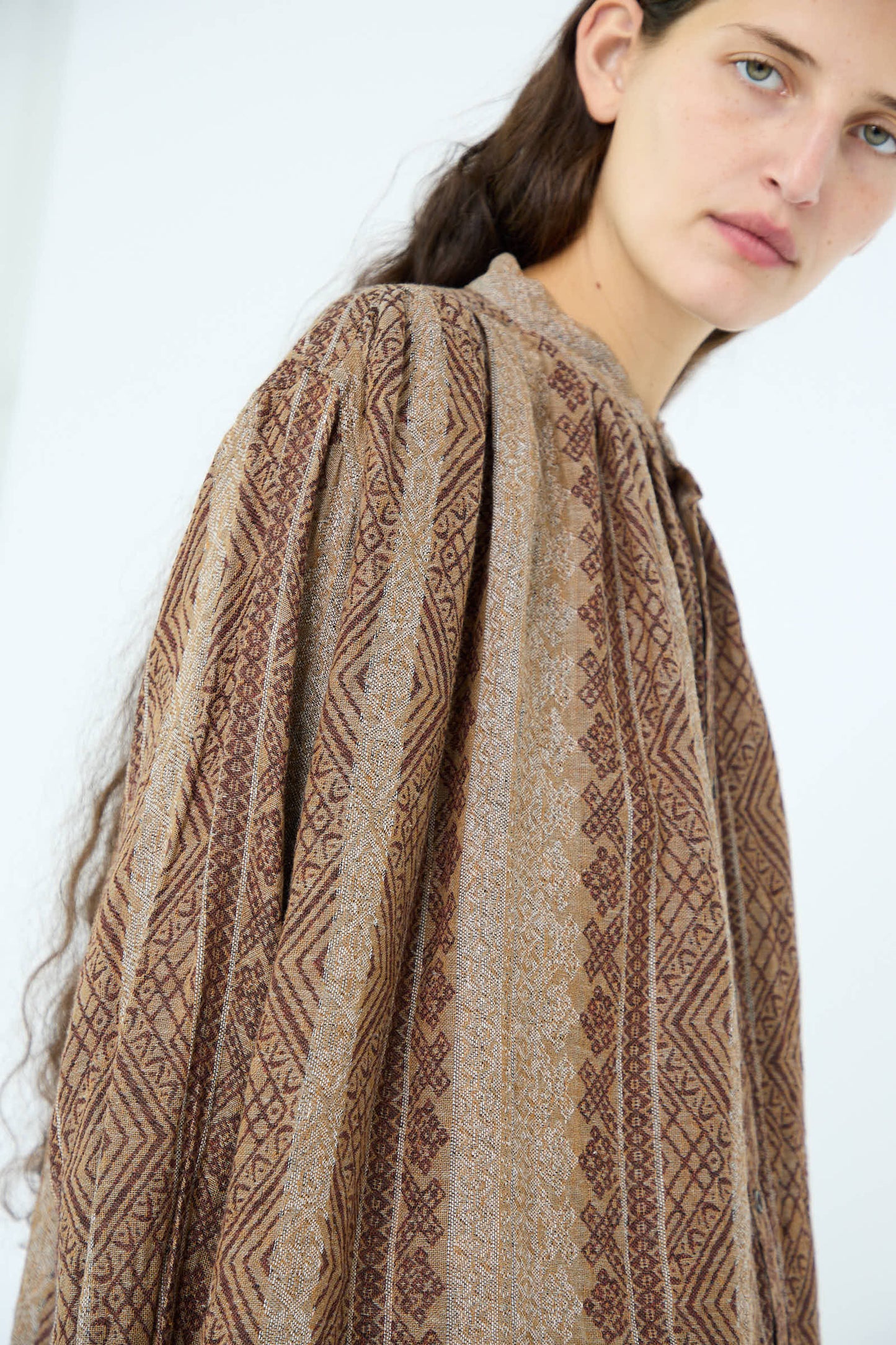 A person wearing the Linen Cotton Jacquard Shirt in Brown by Ichi Antiquités, featuring an oversized patterned design and a band collar, stands against a plain background.