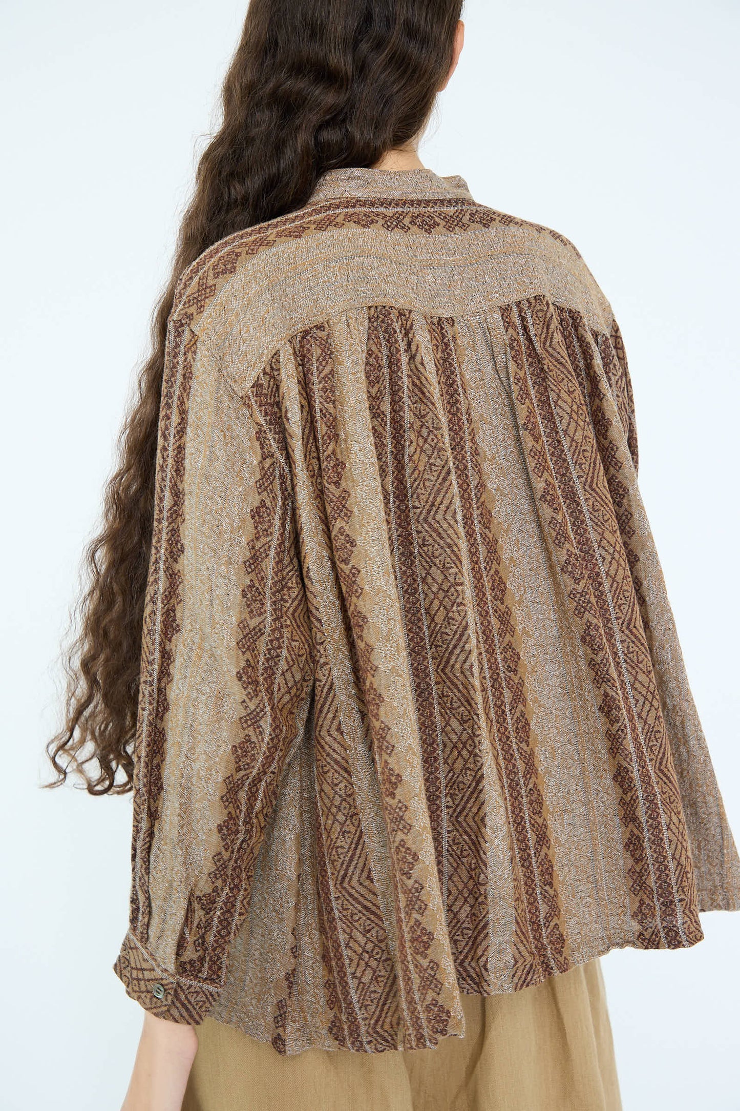 A person with long hair is seen from the back wearing the Ichi Antiquités Linen Cotton Jacquard Shirt in Brown, an oversized piece featuring a band collar and crafted from a soft linen/cotton jacquard blend.