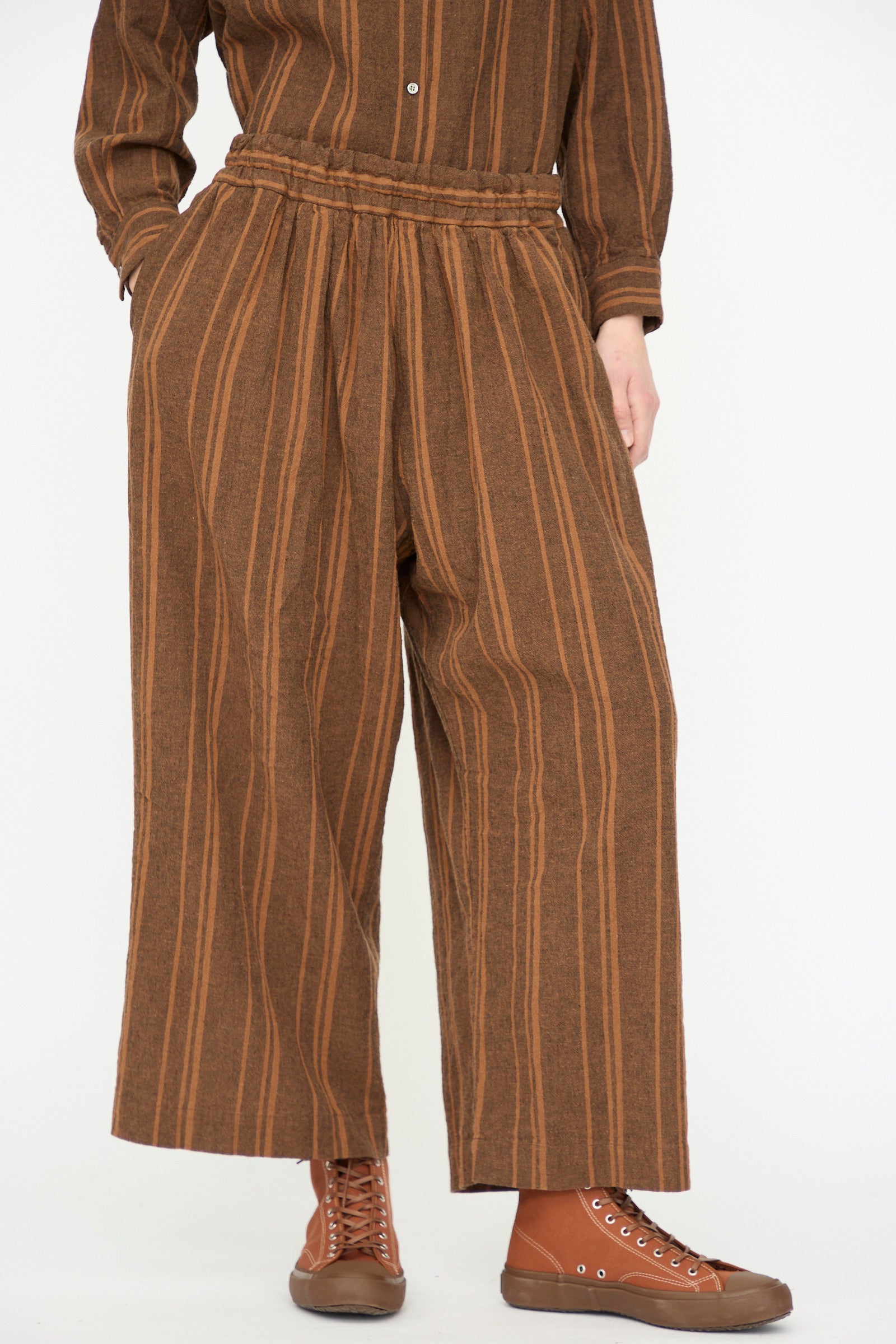 Wearing the Ichi Antiquités Linen Cotton Random Stripe Pant in Brown, this person stands against a plain white background.