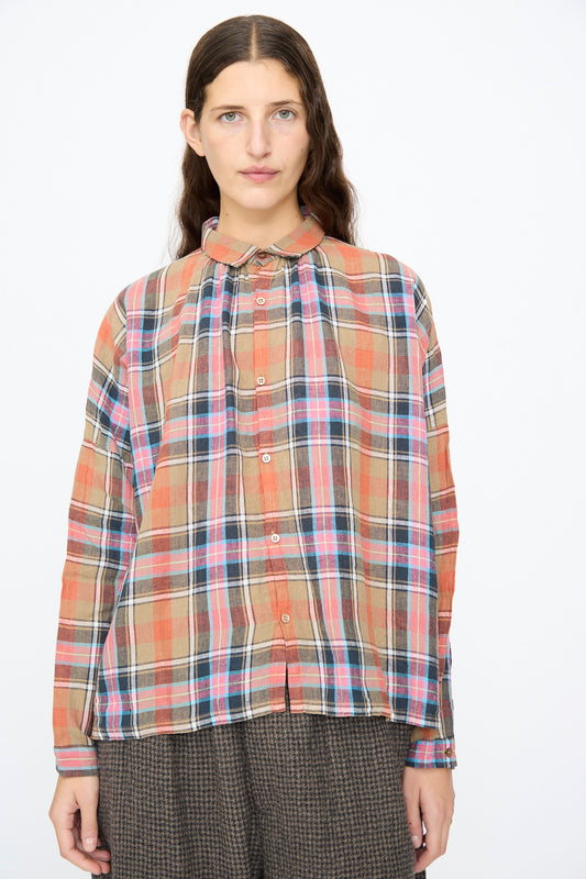 A person wearing an Ichi Antiquités Linen Cotton Tartan Check Shirt in Beige, featuring a long-sleeved, beige, pink, and blue plaid pattern with a small collar.