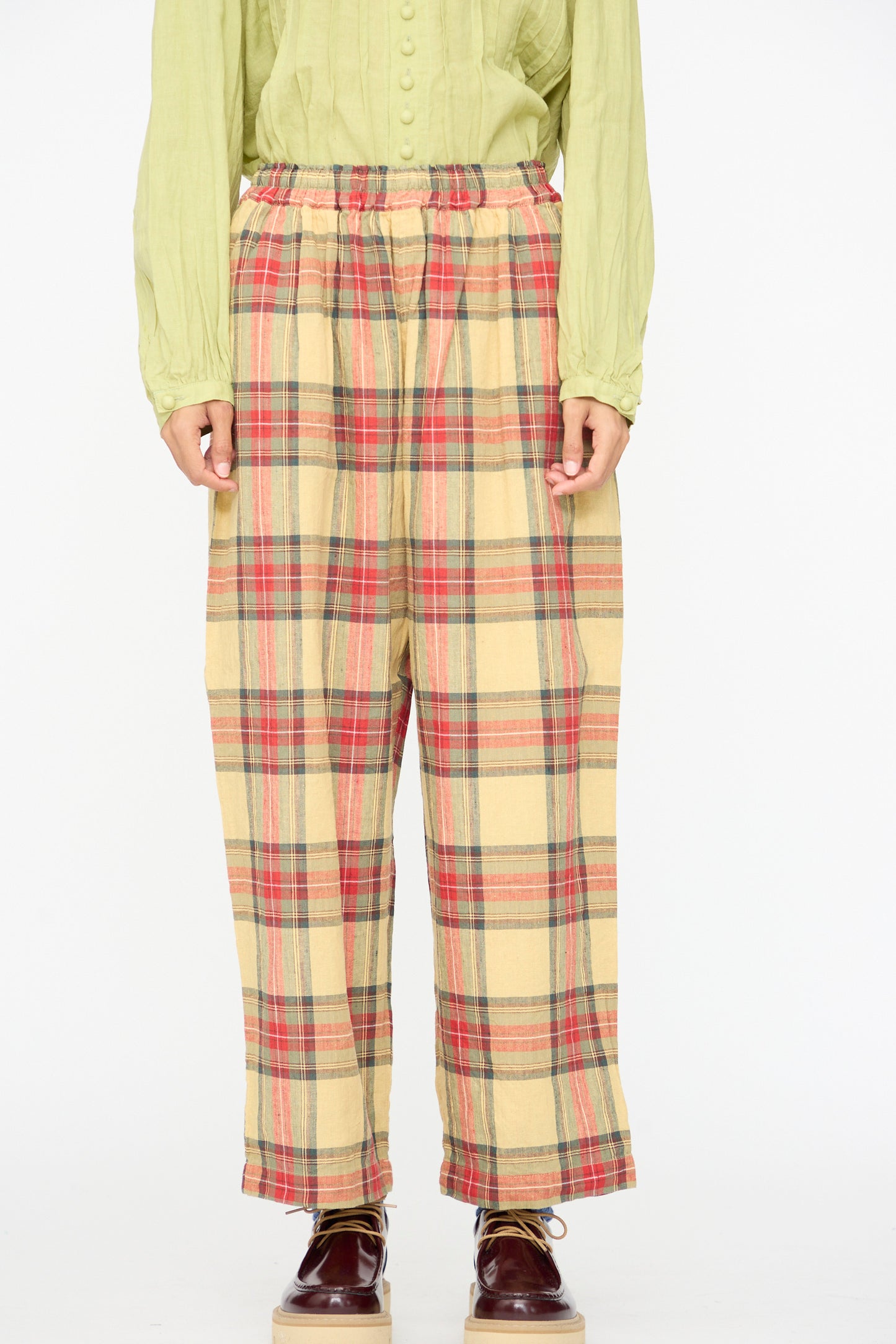 A model wears Ichi Antiquités Linen Cotton Tartan Pants in Butter Yellow, paired with a light green long-sleeve shirt and brown shoes, standing against a plain white background.