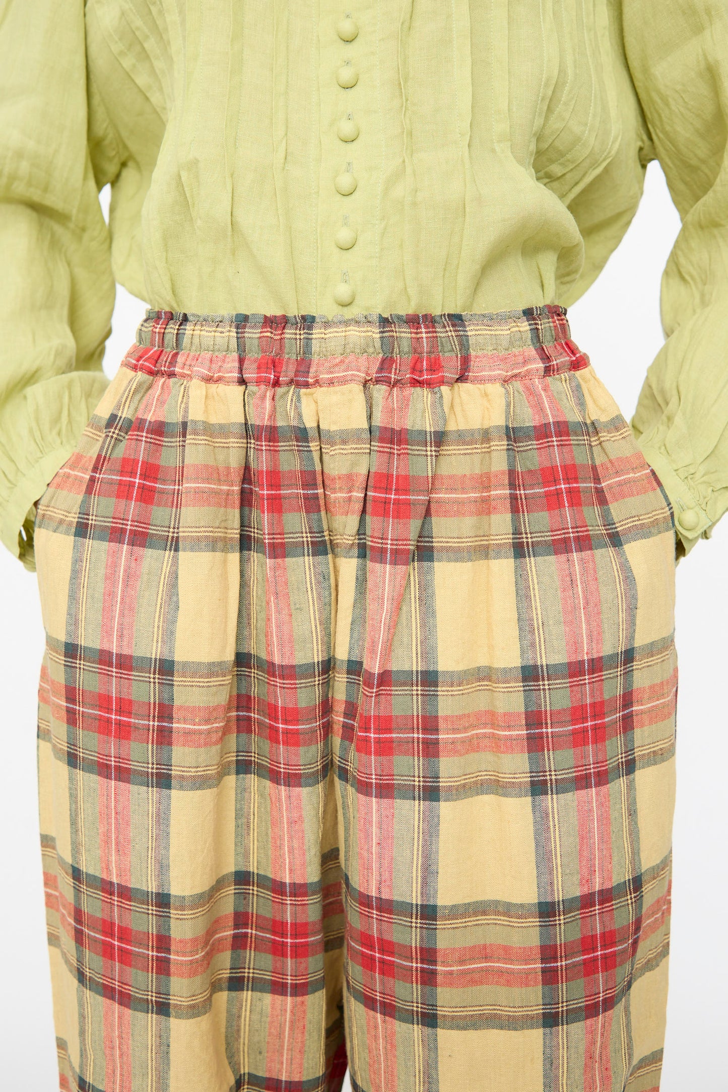 Person wearing a light green buttoned blouse with long sleeves and Ichi Antiquités Linen Cotton Tartan Pants in Butter Yellow, hands in pockets.