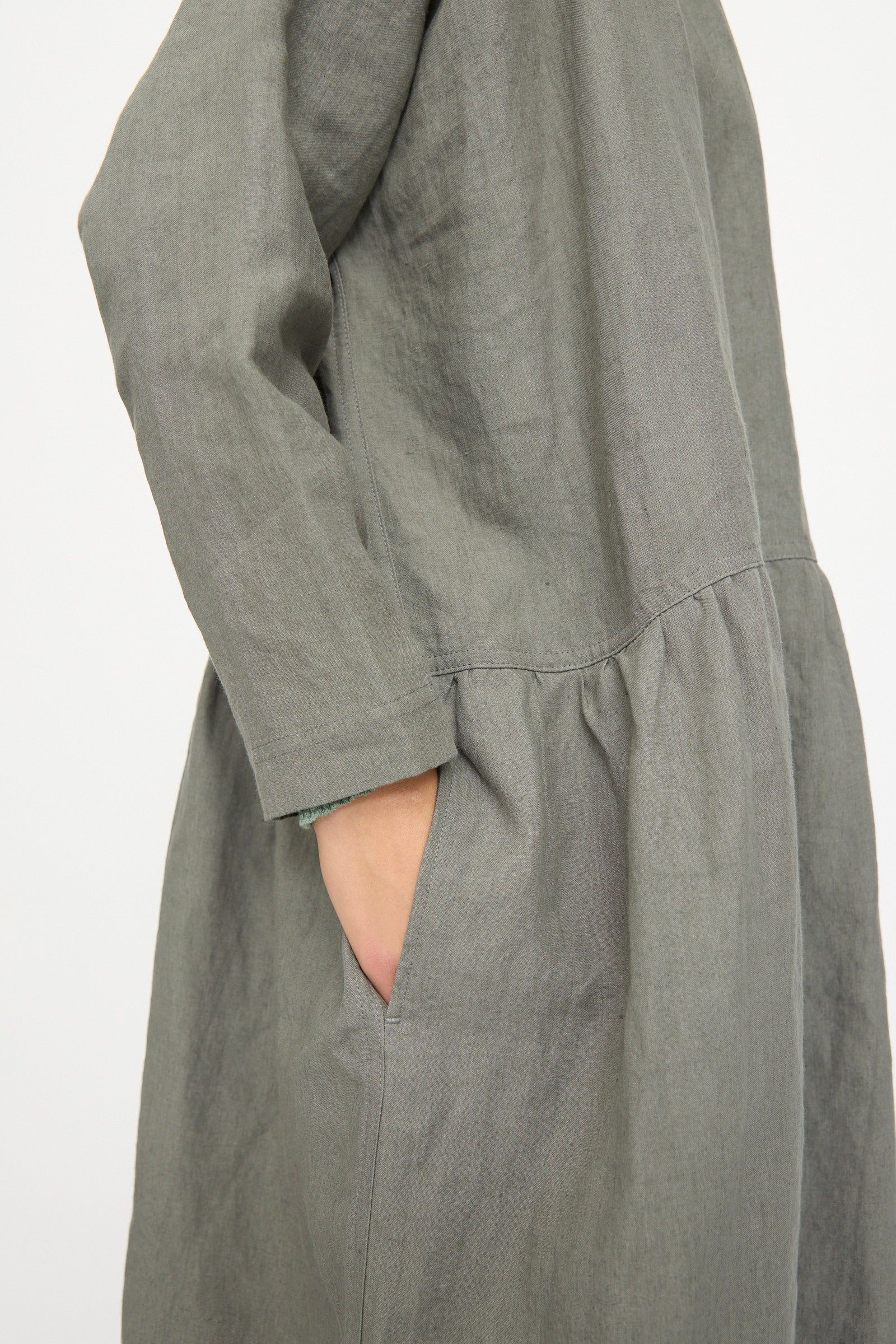 A person wearing the Ichi Antiquités Linen Dress in khaki, featuring a loose fit, long sleeves, and side pockets; made in Japan.