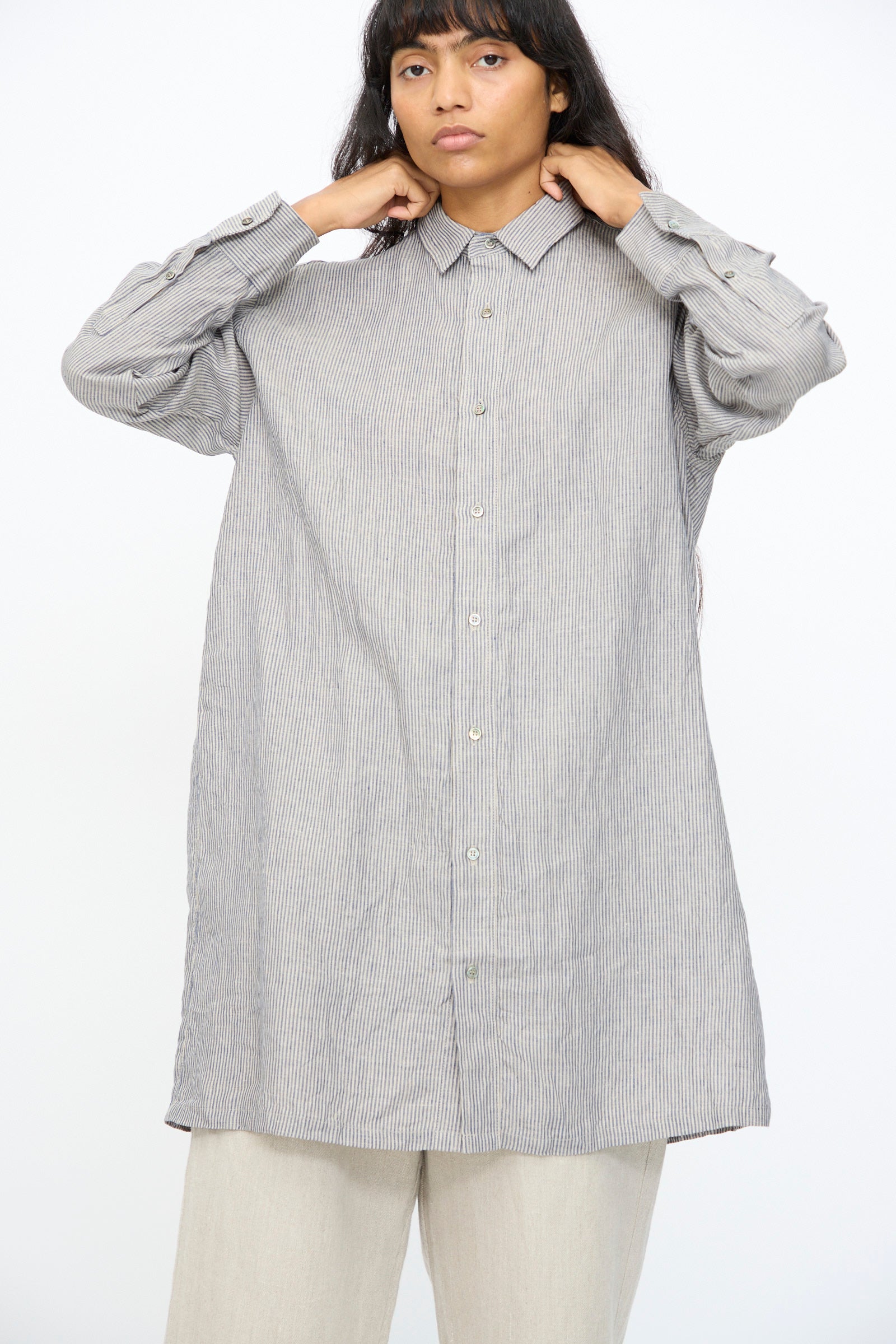 A person wears the Ichi Antiquités Linen Dungaree Shirt in Stripe with light-colored pants, standing against a plain white background.