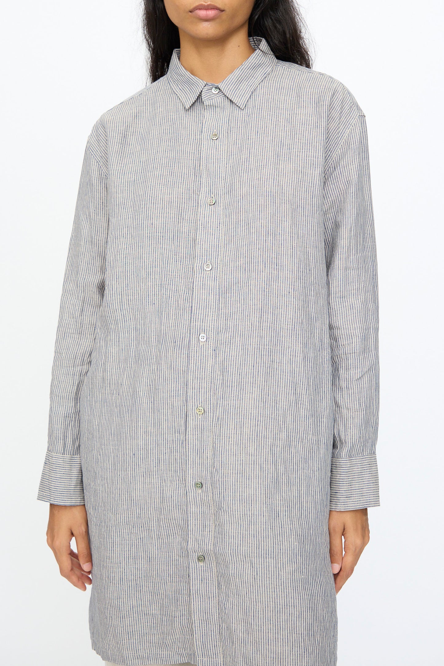 A person wearing the Ichi Antiquités Linen Dungaree Shirt in Stripe—light grey and white—stands against a plain white background.