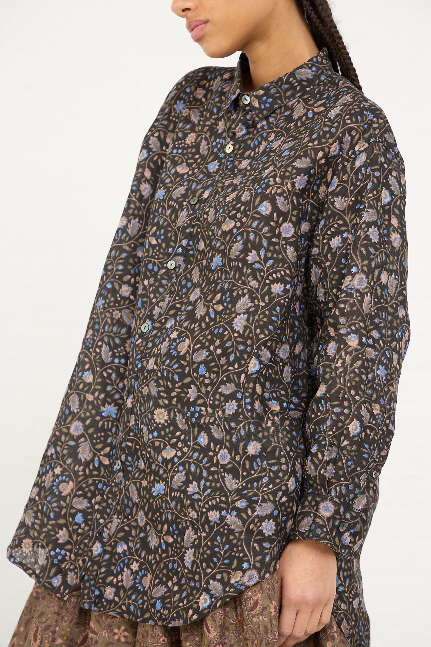 A person wearing a Black Linen Floral Shirt by Ichi Antiquités with a high neckline and long sleeves.