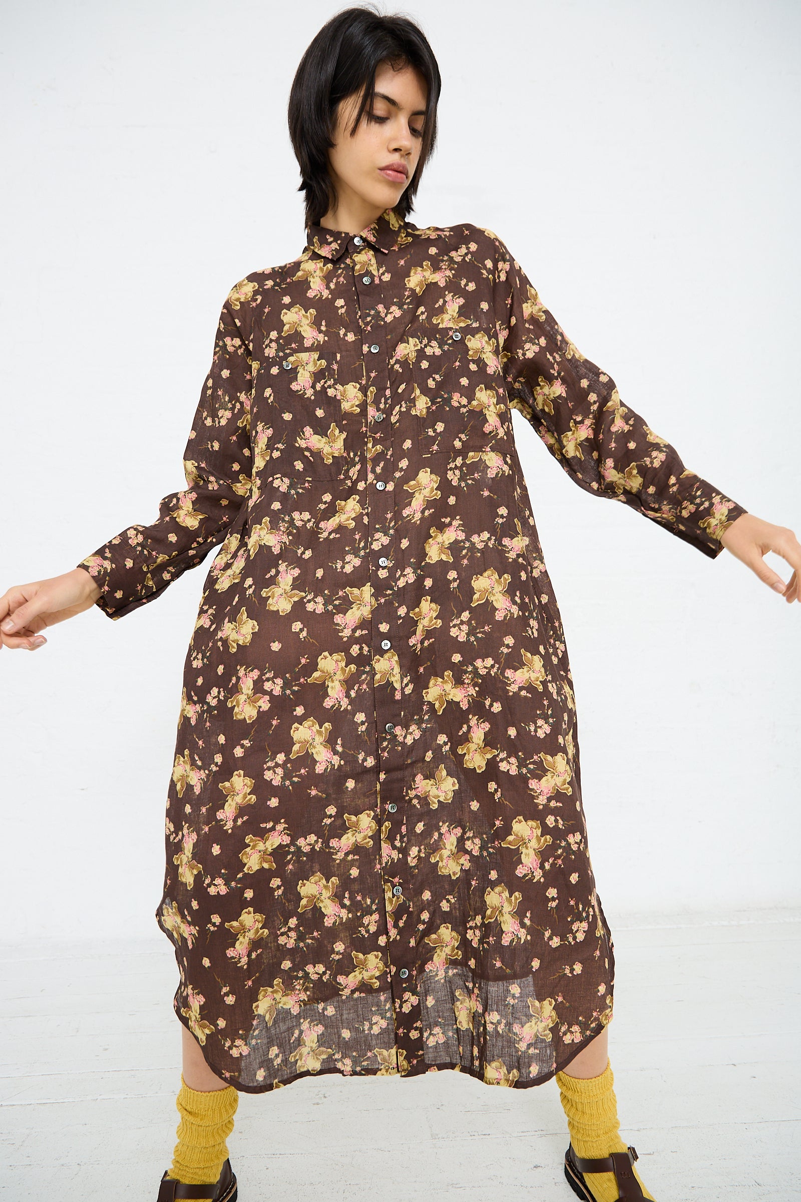 Person wearing a long-sleeved, Ichi Antiquités Linen Flower Print Dress in Brown stands against a plain white background. They have mustard-colored socks and black shoes.