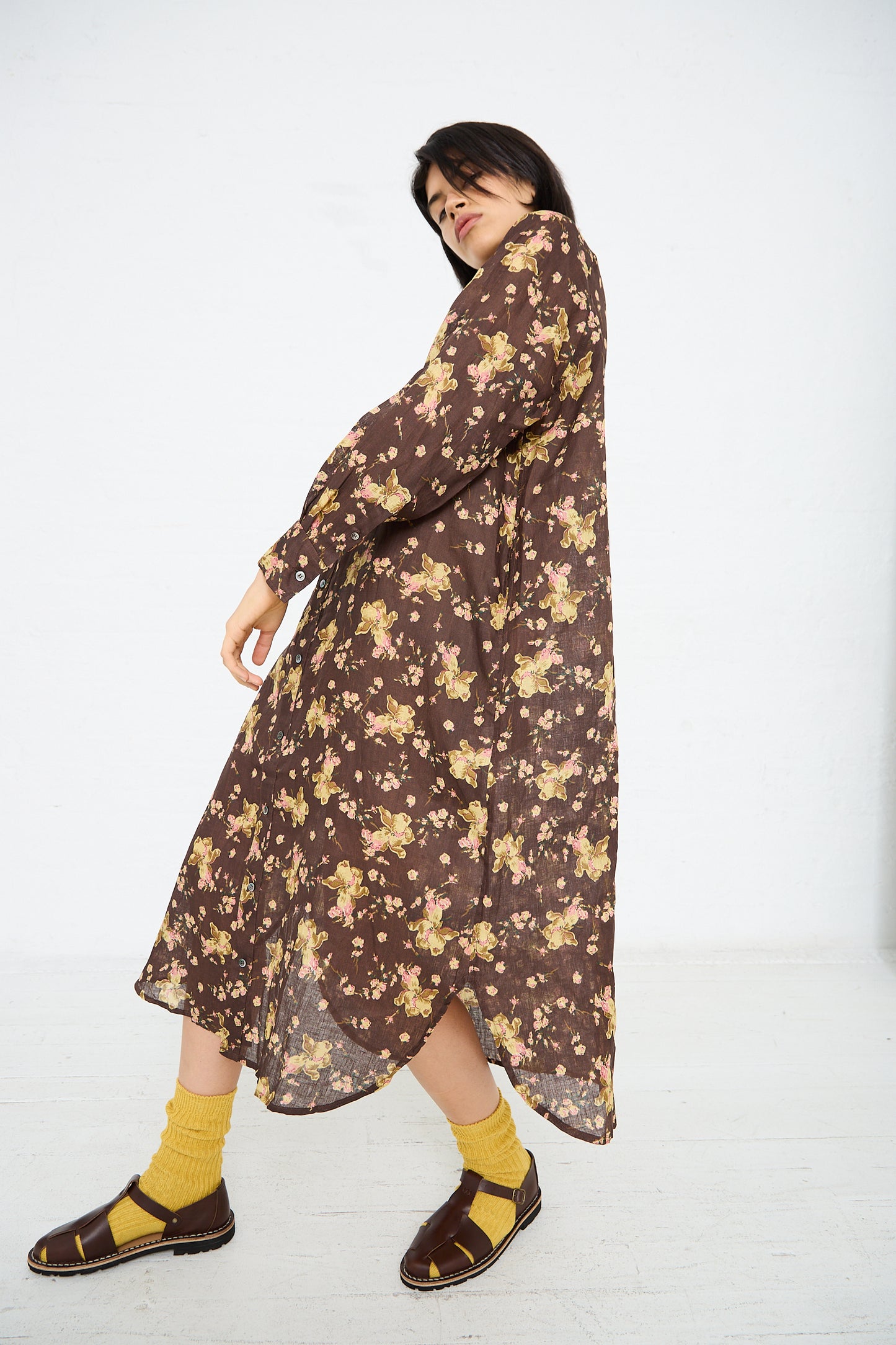 Person wearing the Linen Flower Print Dress in Brown by Ichi Antiquités, yellow socks, and brown sandals, posing against a plain white background.