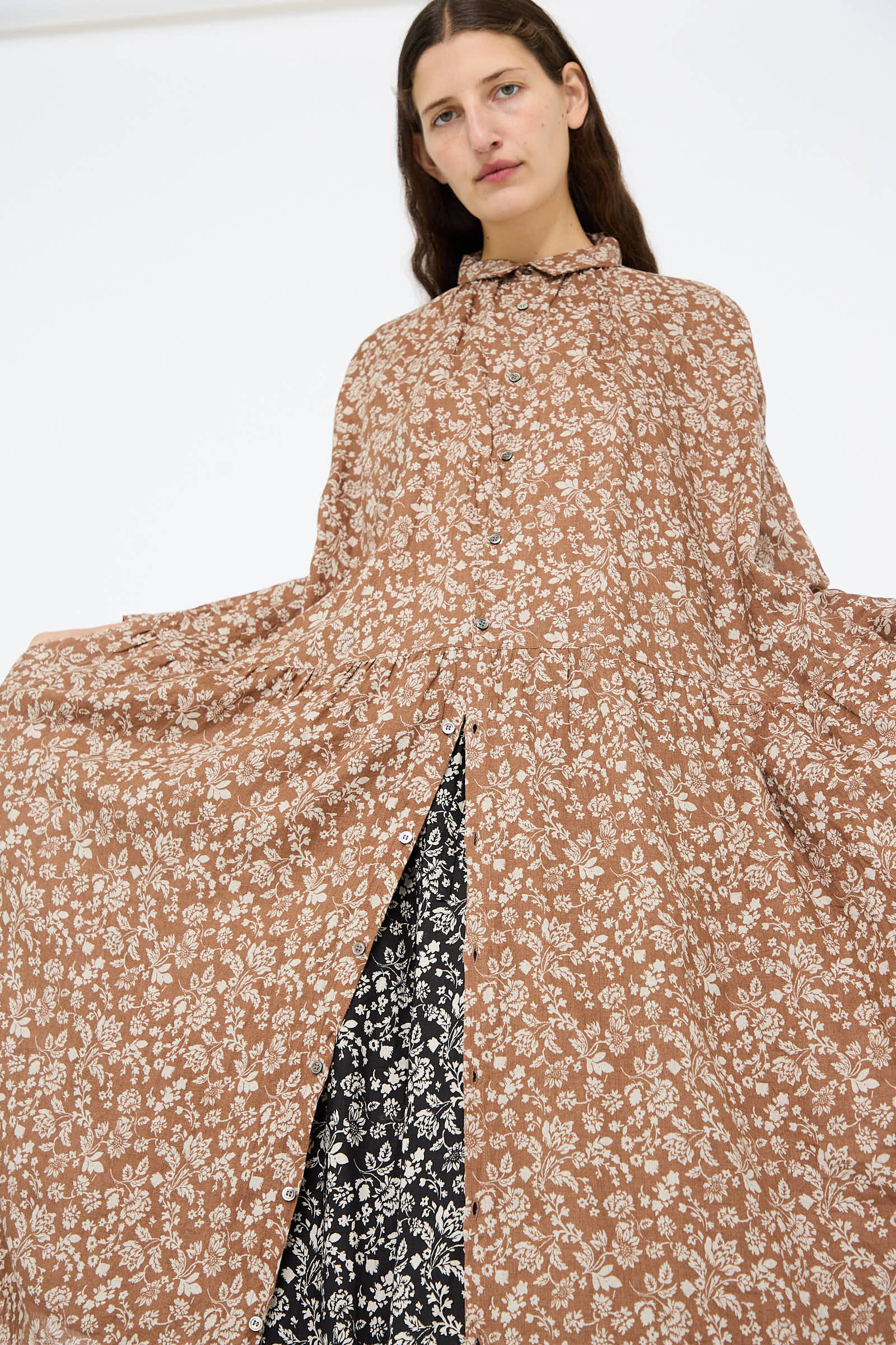 A person wearing the Linen Flower Print Dress in Brown by Ichi Antiquités over a black and white floral skirt stands against a plain white background.