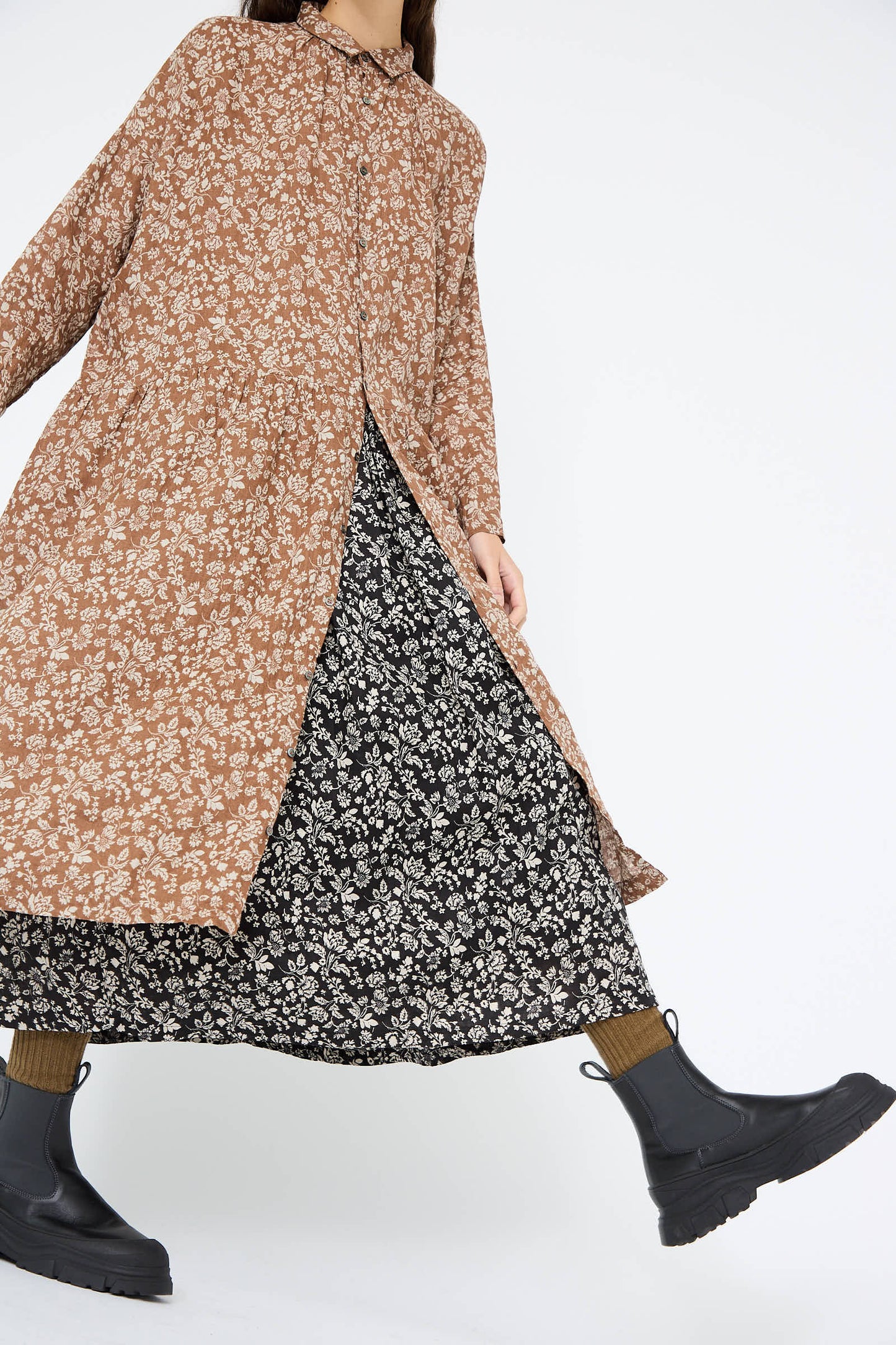 A person wearing the Linen Flower Print Dress in Brown by Ichi Antiquités, styled with black boots, walking with one foot forward.