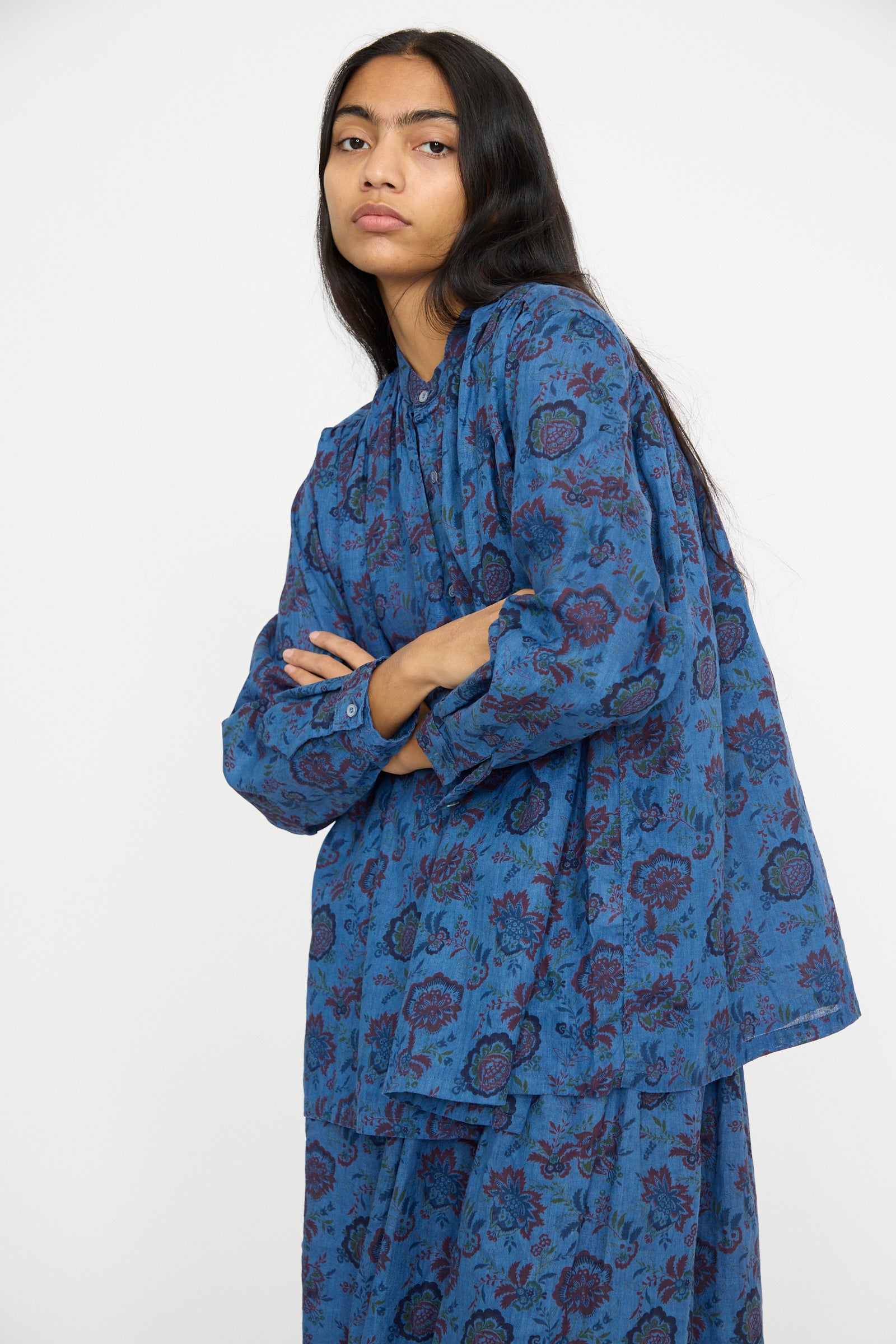 A person with long hair wears an Ichi Antiquités Linen Flower Shirt in Overdye Blue and a matching relaxed-fit skirt, standing against a plain white background.