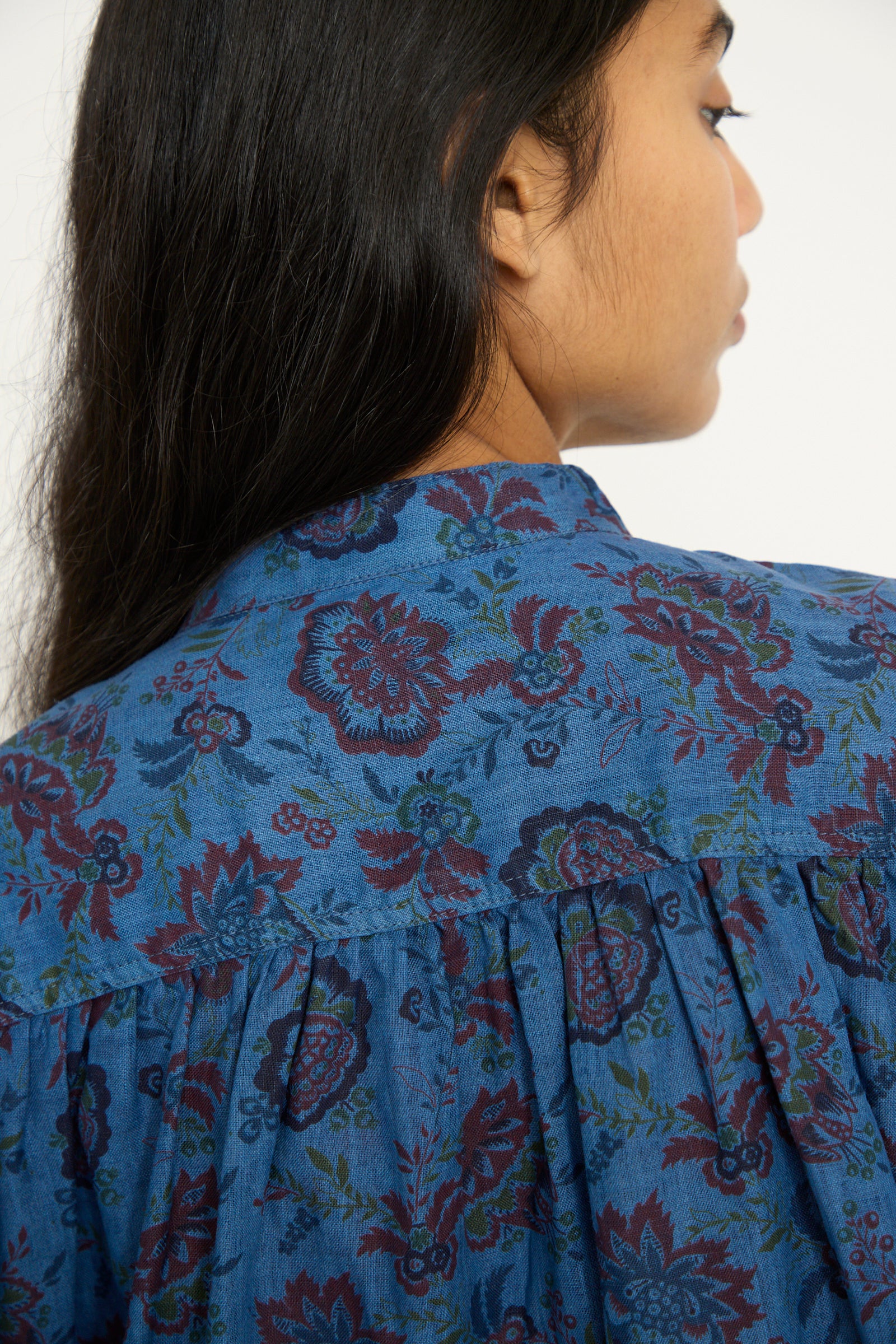 A person with long dark hair is seen from the back wearing a relaxed fit Ichi Antiquités Linen Flower Shirt in Overdye Blue.