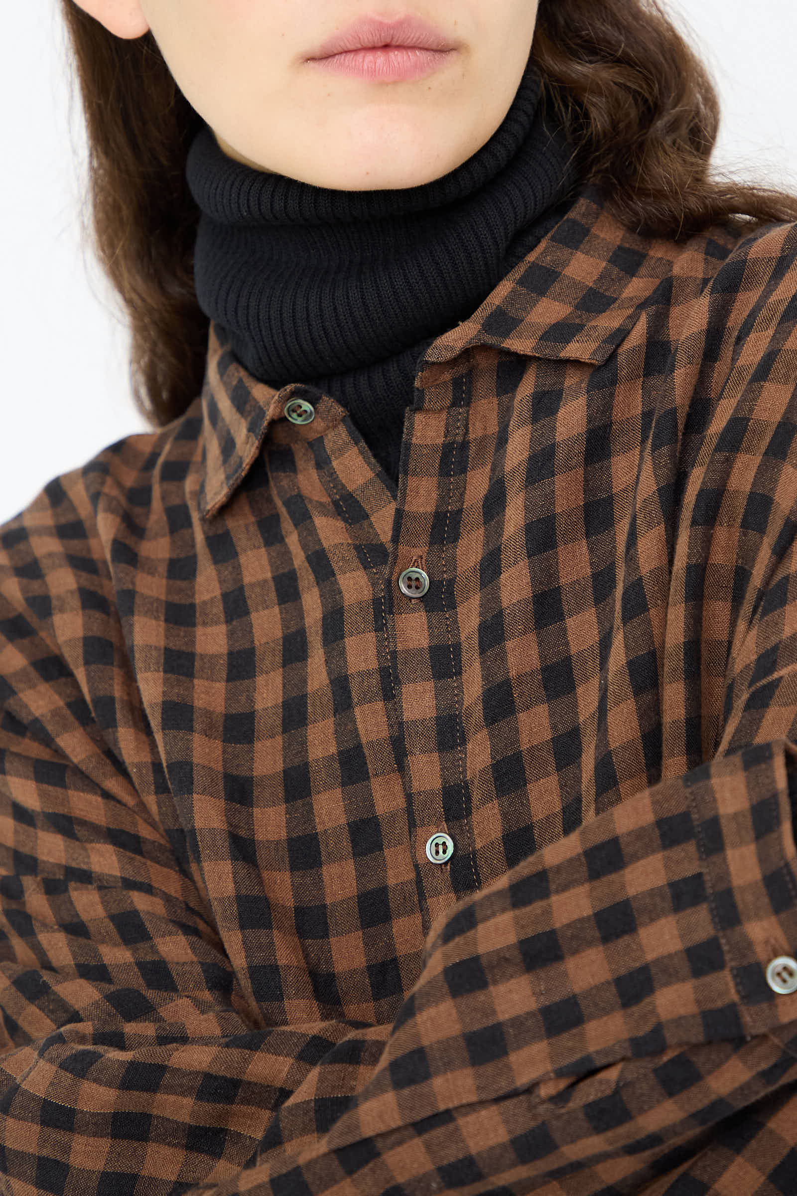 A person wearing an oversized Linen Gingham Check Shirt in Brown by Ichi Antiquités over a black turtleneck.