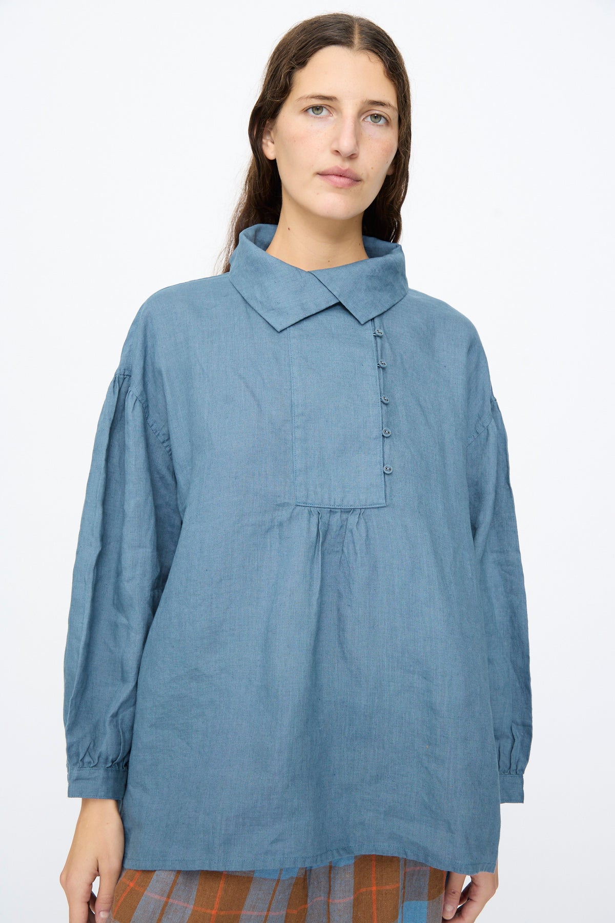 A woman wears an Ichi Antiquités Linen Shirt in Earth Blue, a relaxed fit, long-sleeved blue button-down with a gathered yoke and a pointed collar.