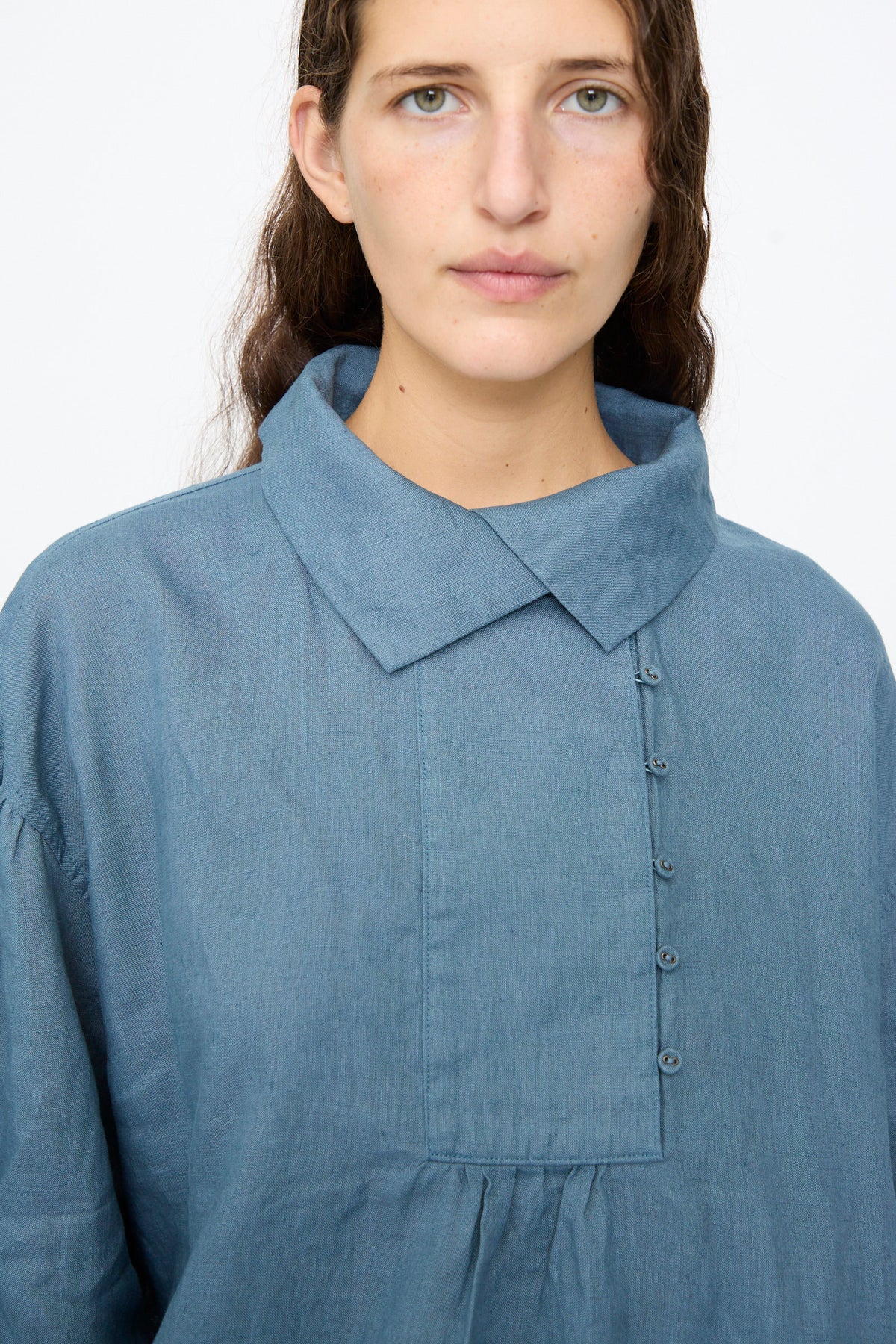 A person wearing an Ichi Antiquités Linen Shirt in Earth Blue, a relaxed fit collared shirt with an offset button placket.