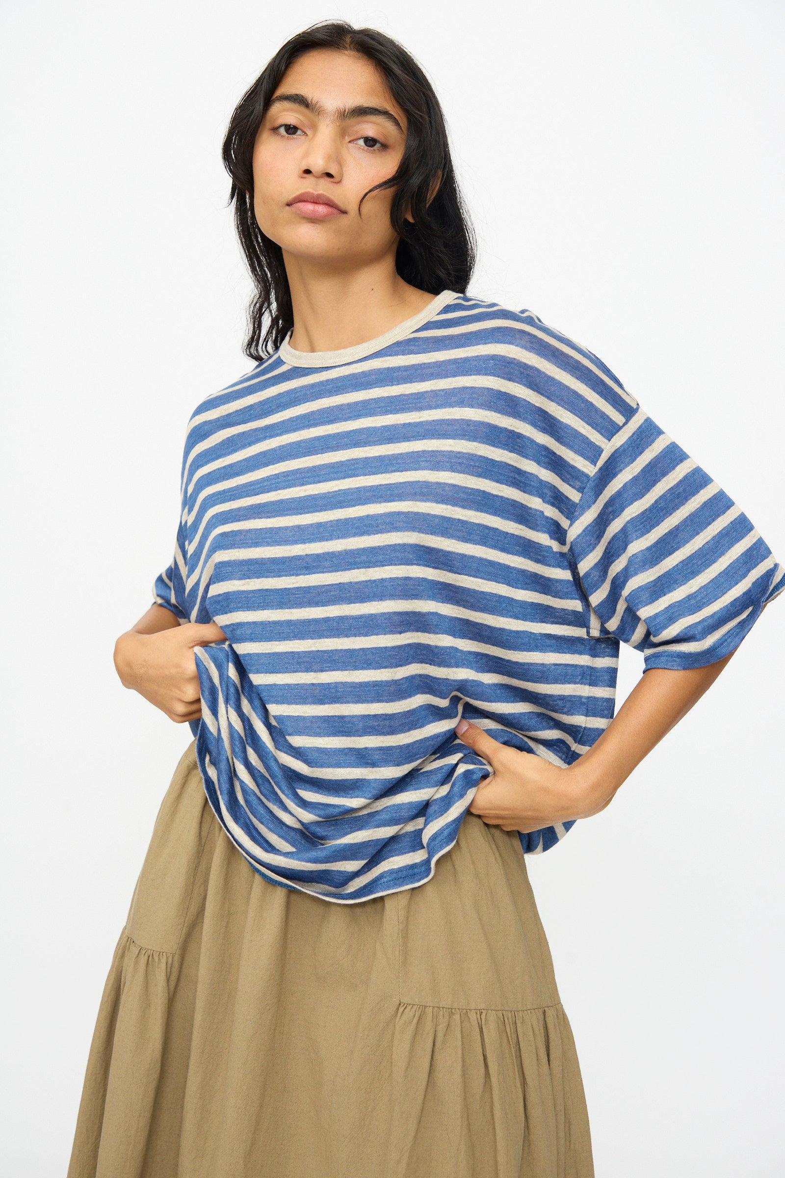 A person in the Ichi Antiquités Linen Stripe Pullover in Blue and Natural with a beige skirt stands against a plain light background.