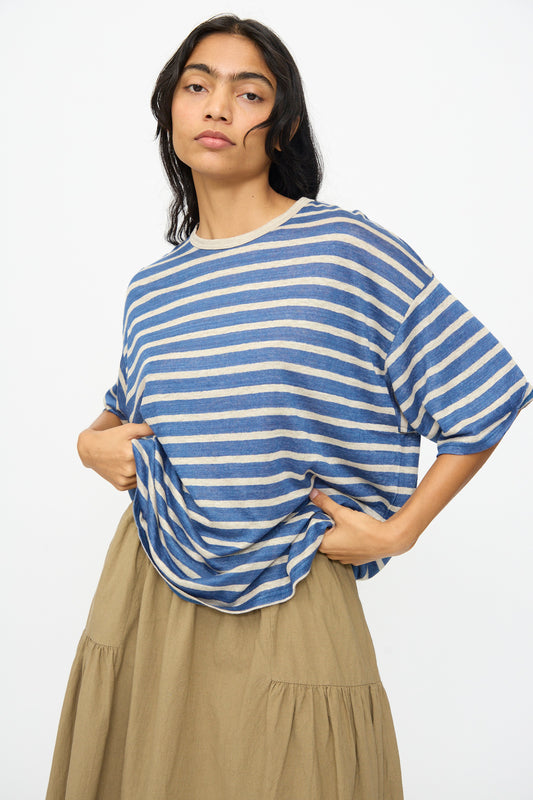 A person in the Ichi Antiquités Linen Stripe Pullover in Blue and Natural with a beige skirt stands against a plain light background.