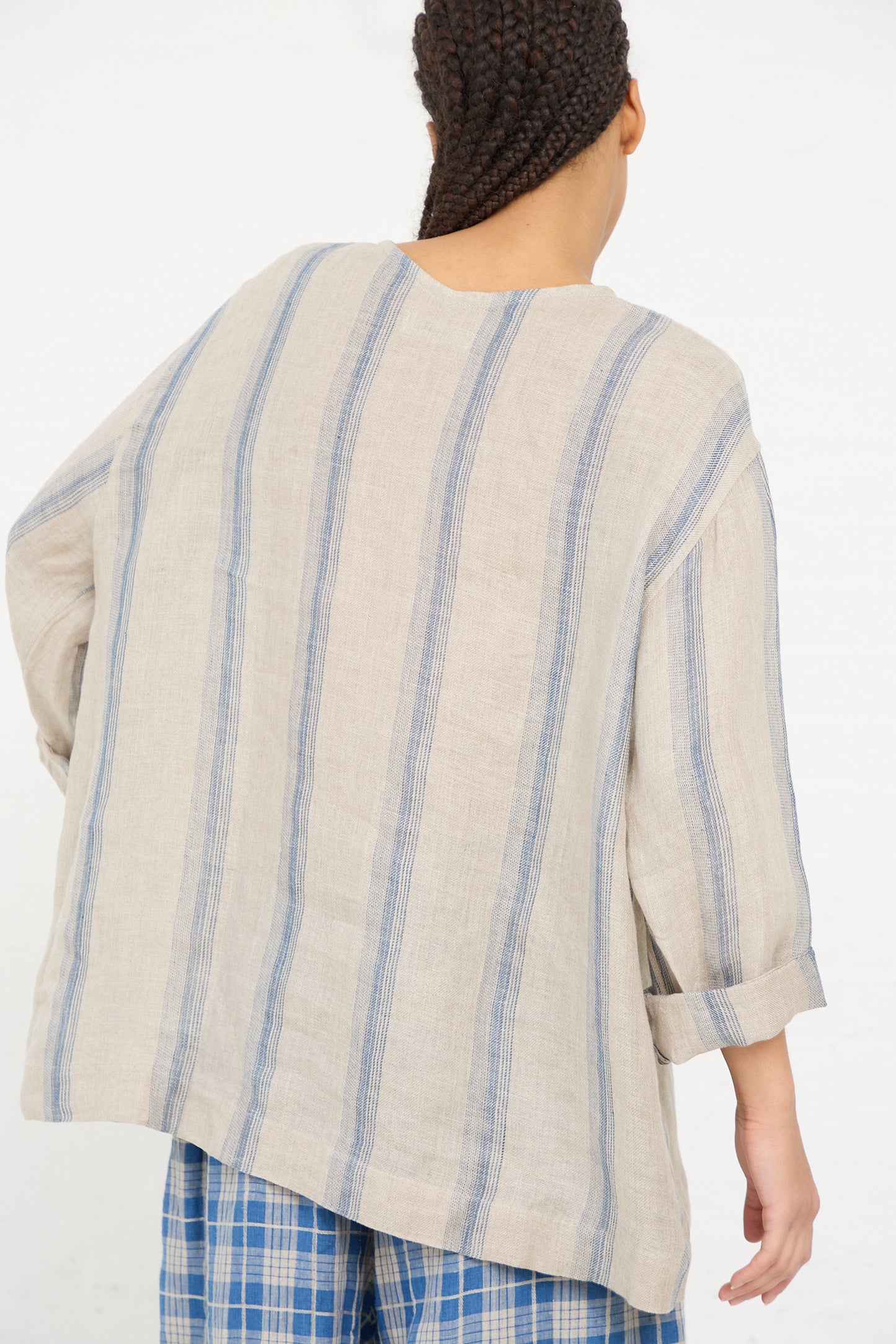 A person seen from the back wearing an Ichi Antiquités Linen Stripe Pullover in Natural and Indigo with rolled-up sleeves.