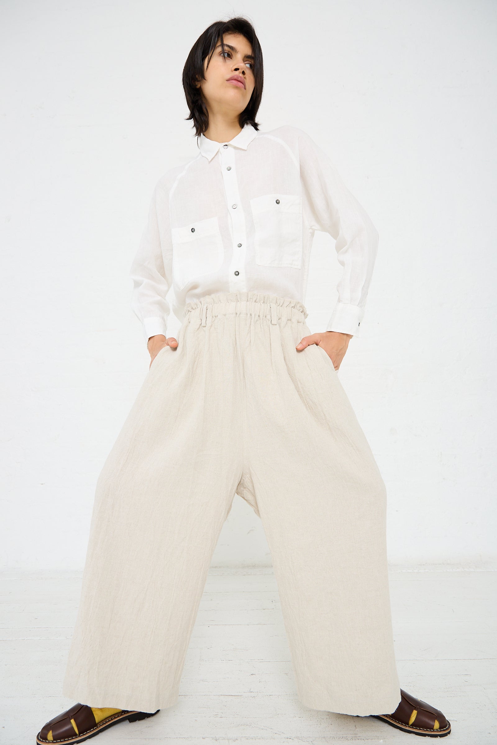 A person in a white button-up shirt and Ichi Antiquités Linen Vintage Pant in Natural stands confidently against a white background.