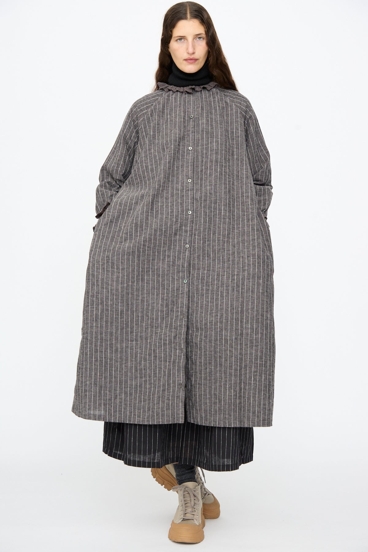 Person wearing an Ichi Antiquités Pinstripe Dress in Charcoal with a lace ruffle collar over a darker pinstripe skirt, paired with beige platform sneakers.