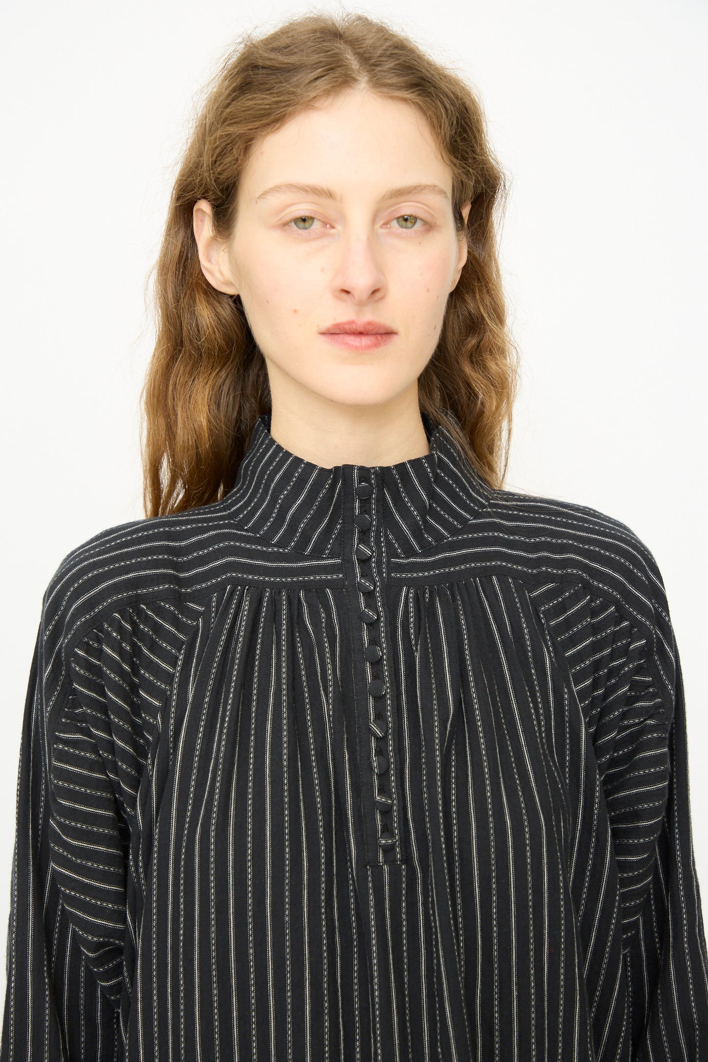 A person with long, wavy brown hair wears the Shirring Brushed Stripe Dress in Black by Ichi Antiquités, featuring white vertical stripes, against a plain white background.
